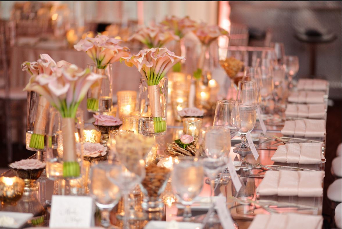 A long table with plates , glasses , and flowers on it.