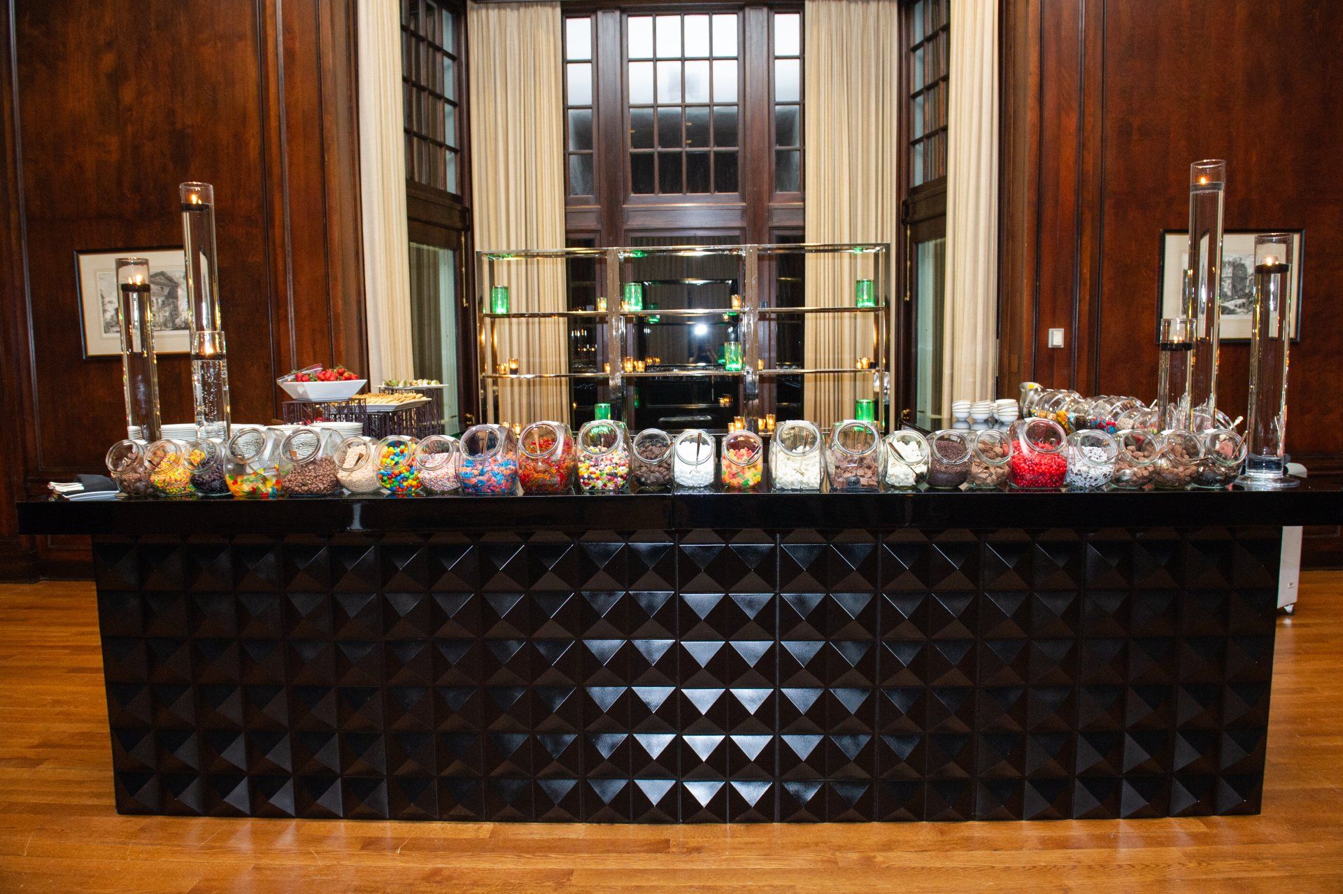 A long black bar filled with jars of candy in a room.