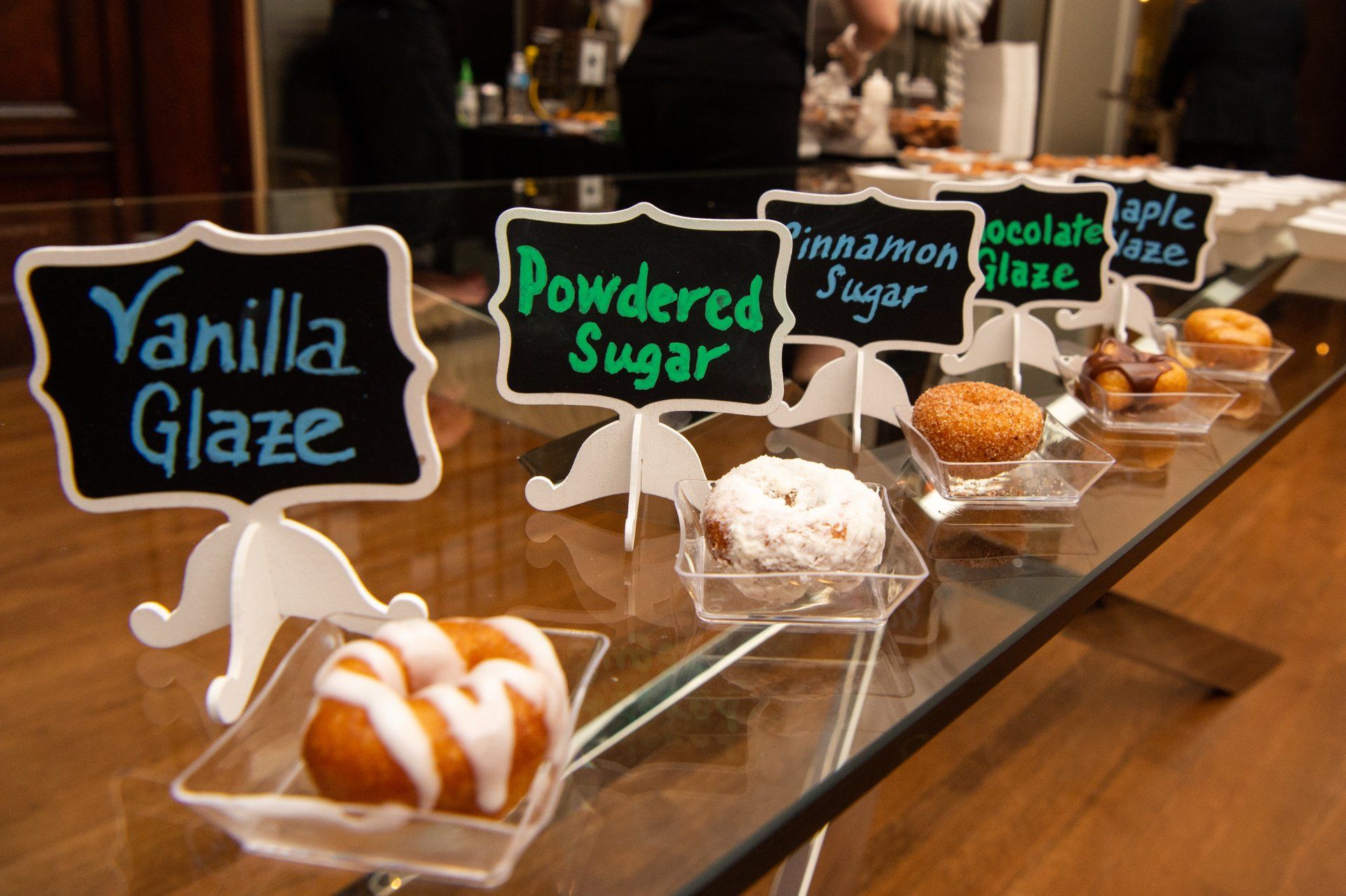 A display of donuts with signs that say vanilla glaze and powdered sugar