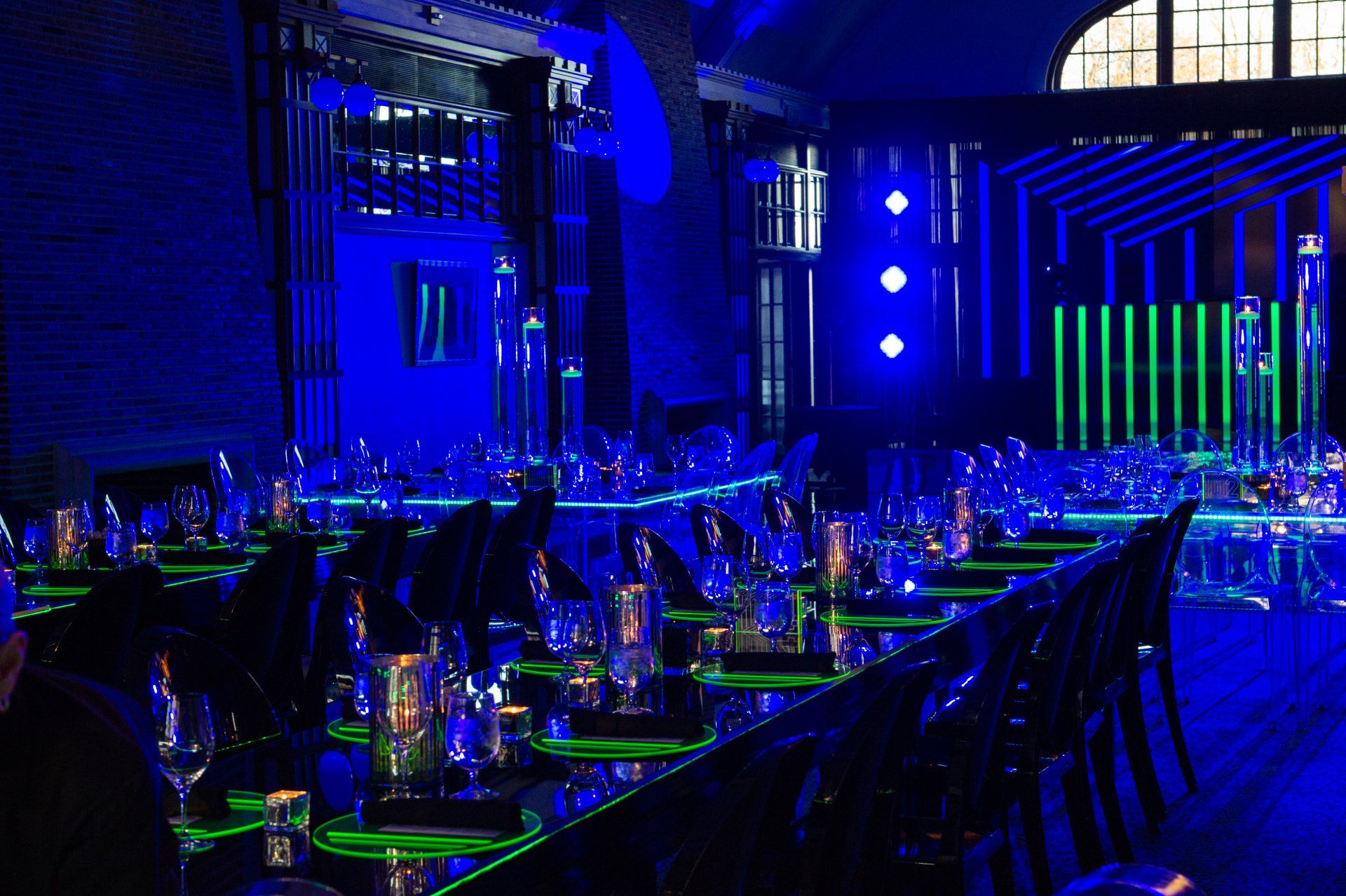 A long table with a lot of glasses on it is sitting in a dark room.