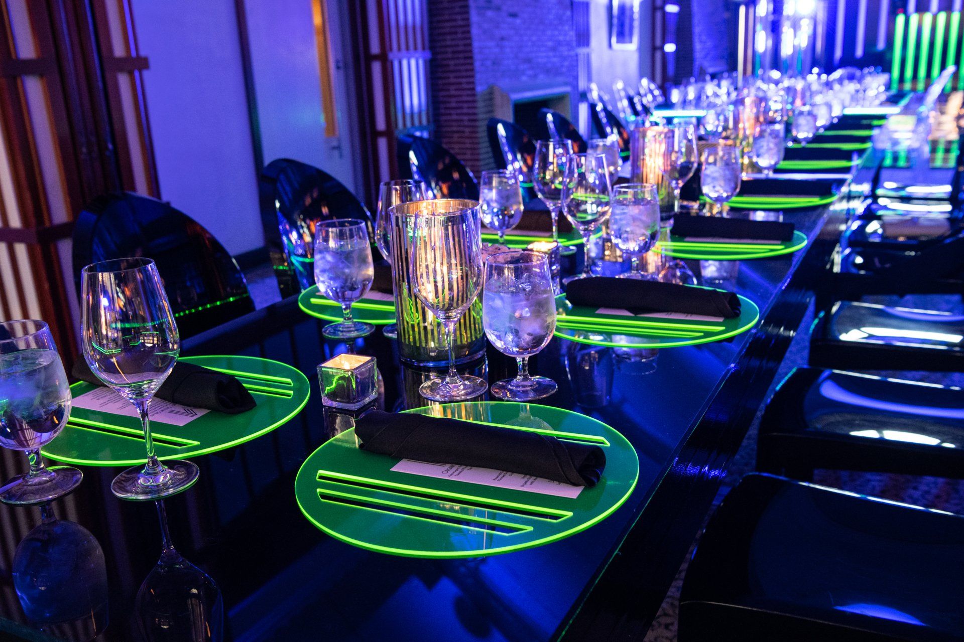 A long table with glow in the dark place mats and wine glasses