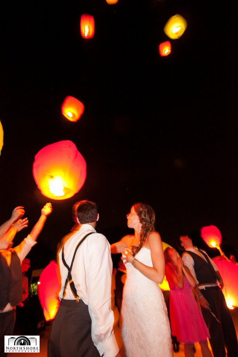 A bride and groom are throwing lanterns into the air