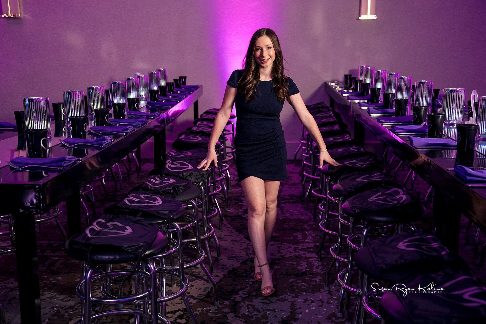 A woman in a black dress is standing in front of a long table.