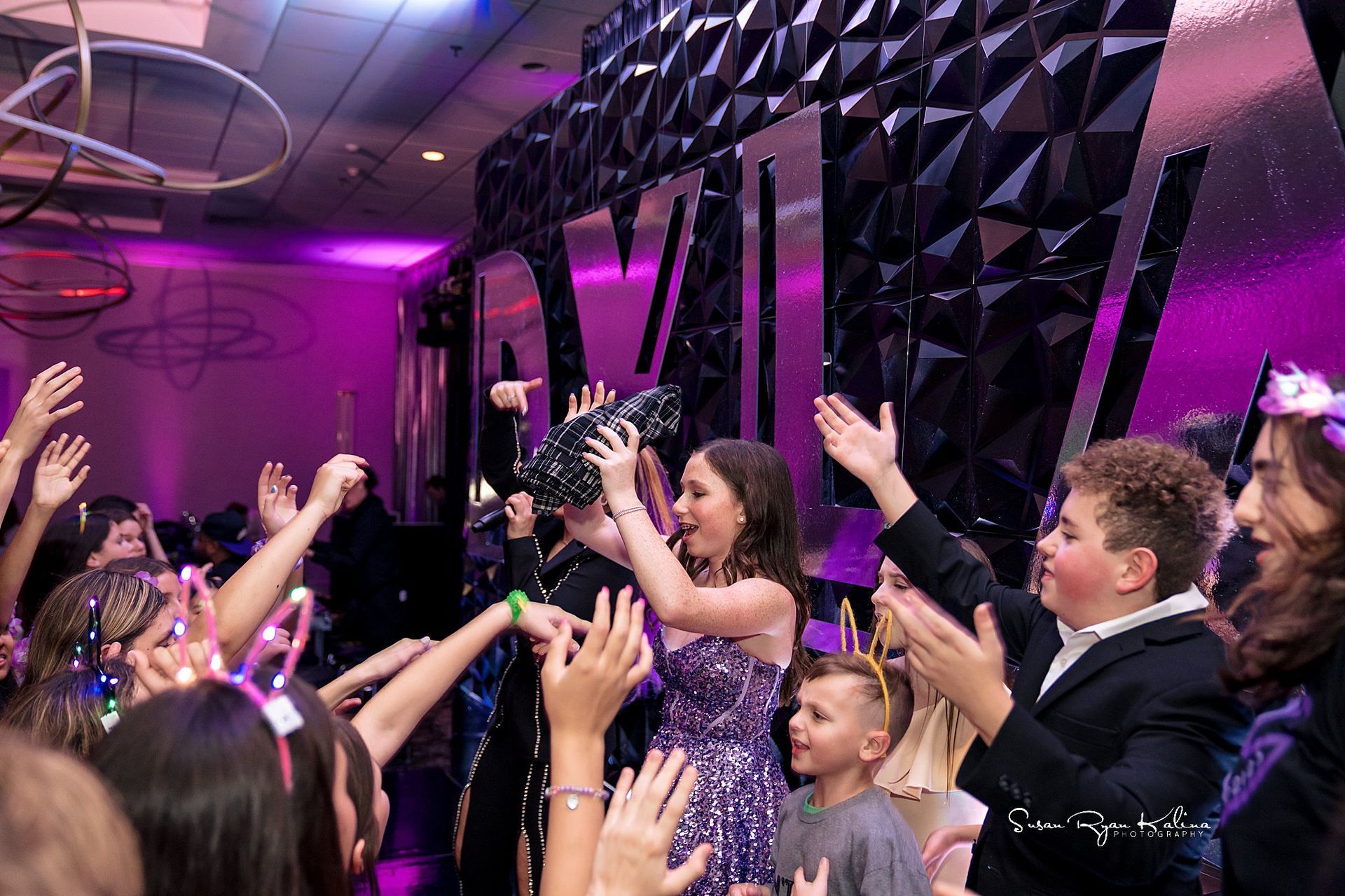 A group of people are standing in a room with their hands in the air.