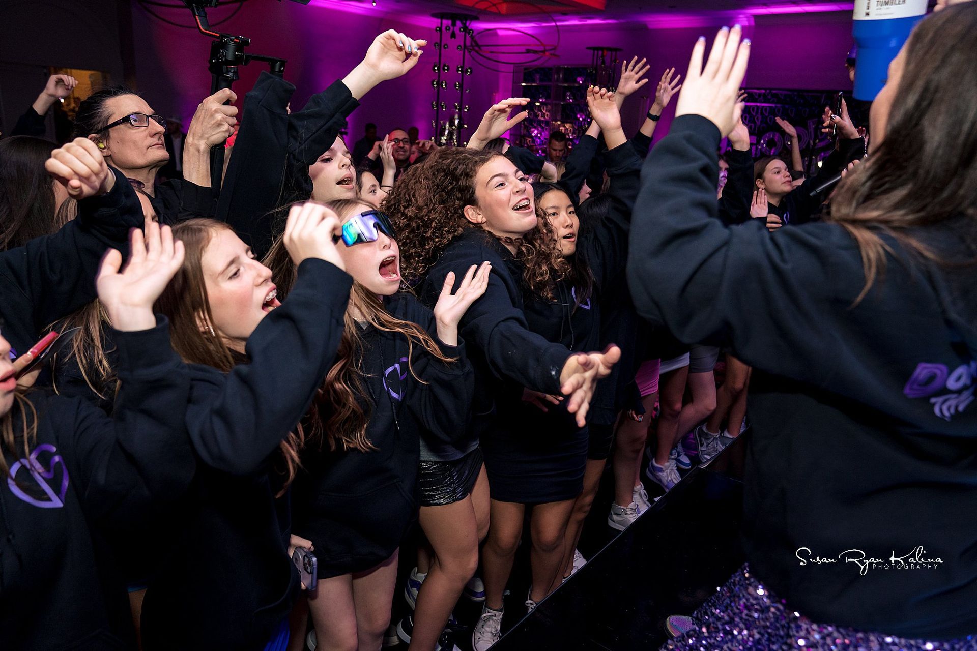 A group of girls are dancing in a room with purple lights.