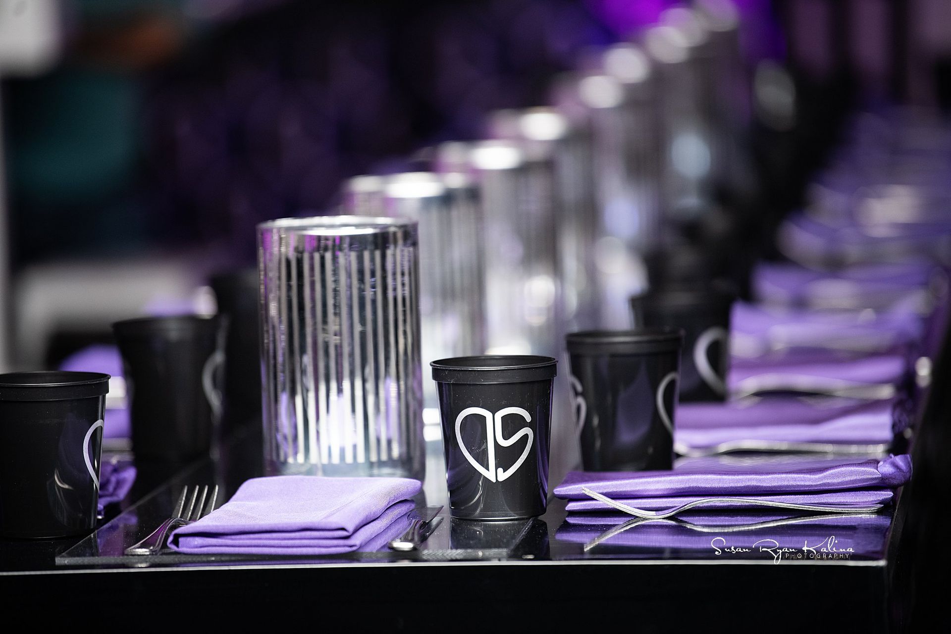 A row of black cups with a heart on them are sitting on a table.