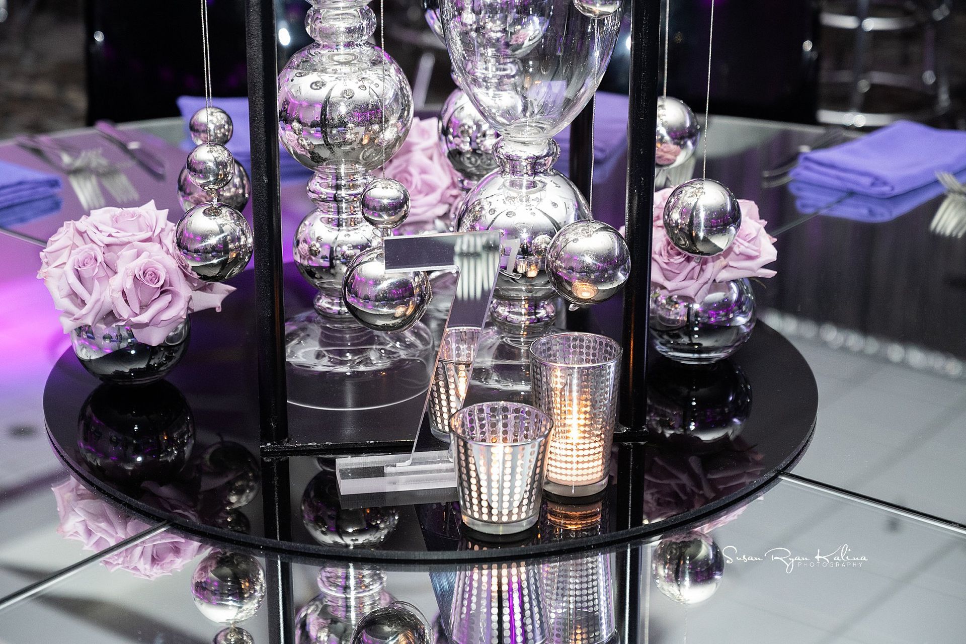 A table with purple flowers and candles on it.