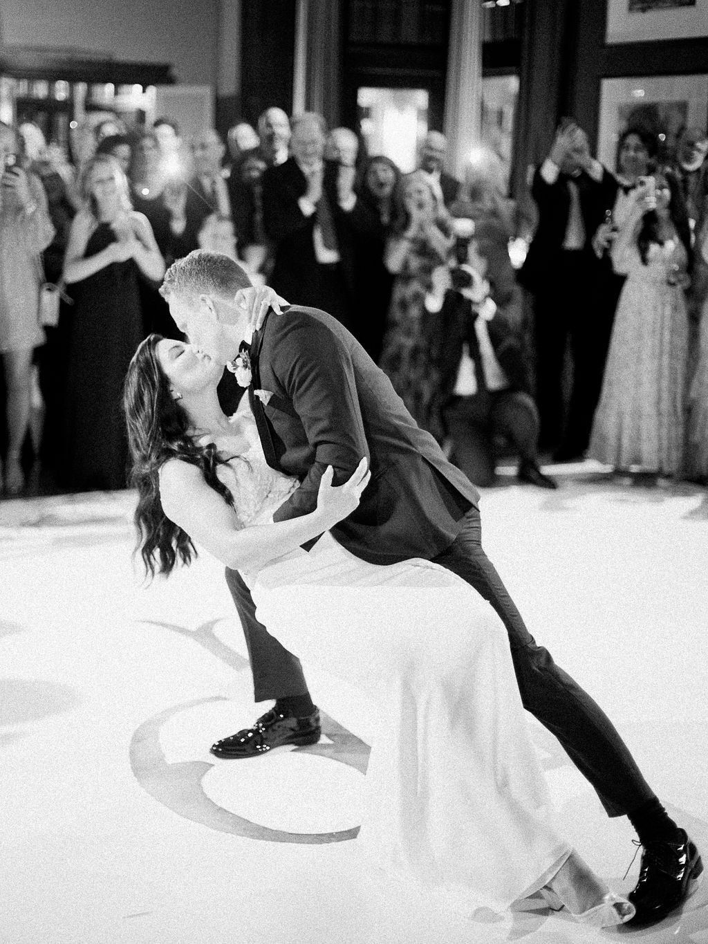 A black and white photo of a bride and groom kissing during their first dance.
