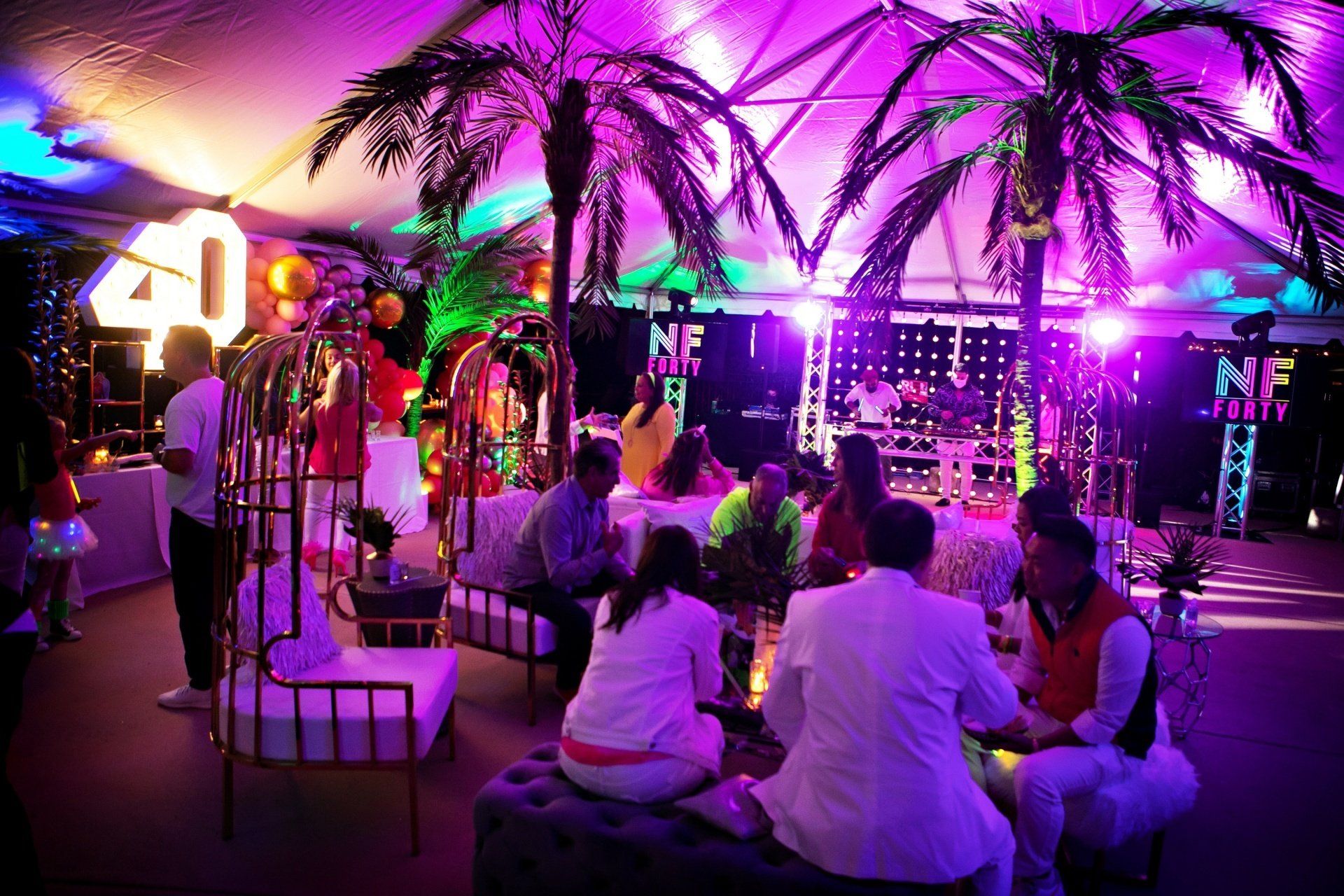 A group of people are sitting in a room with purple lights and a sign that says 40