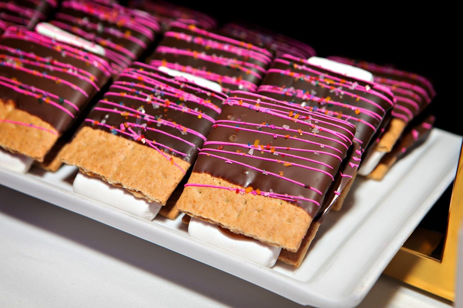 A white plate topped with chocolate covered graham crackers and marshmallows.
