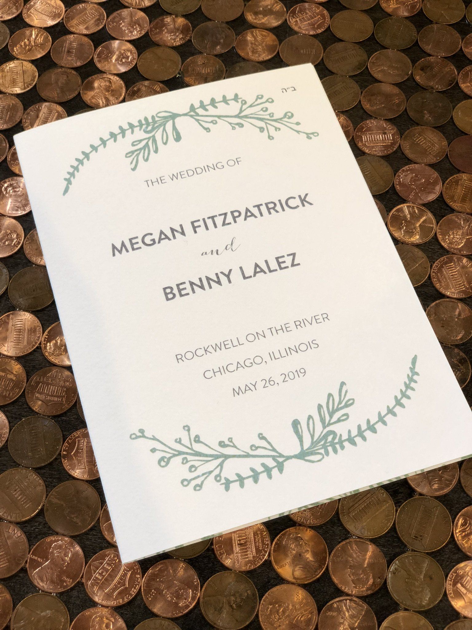 A wedding invitation is sitting on top of a pile of pennies.