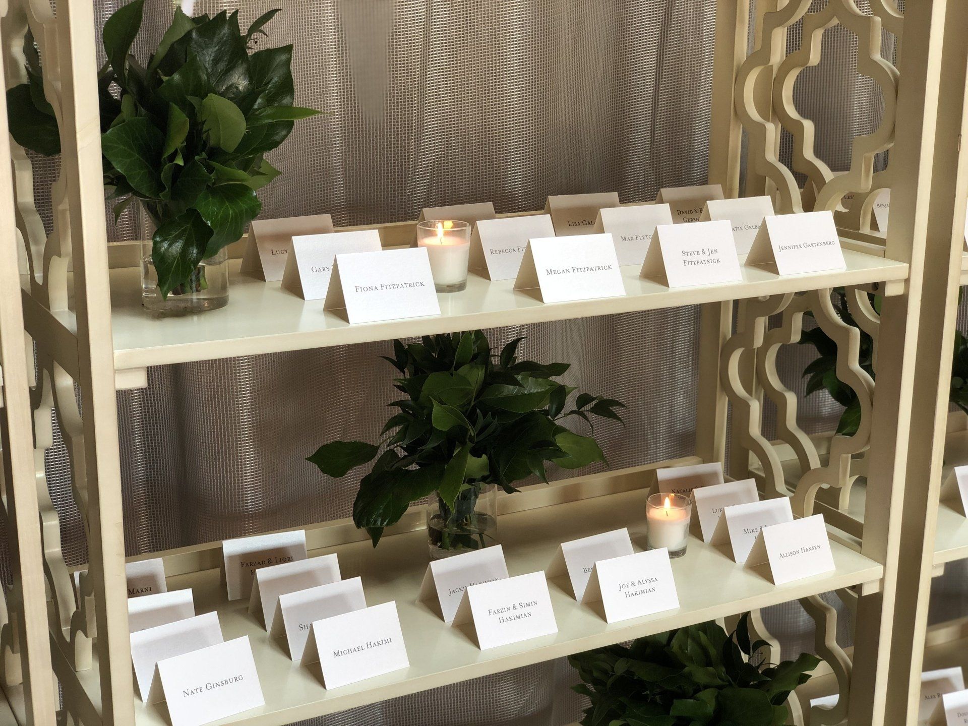 A wooden shelf filled with place cards and candles.