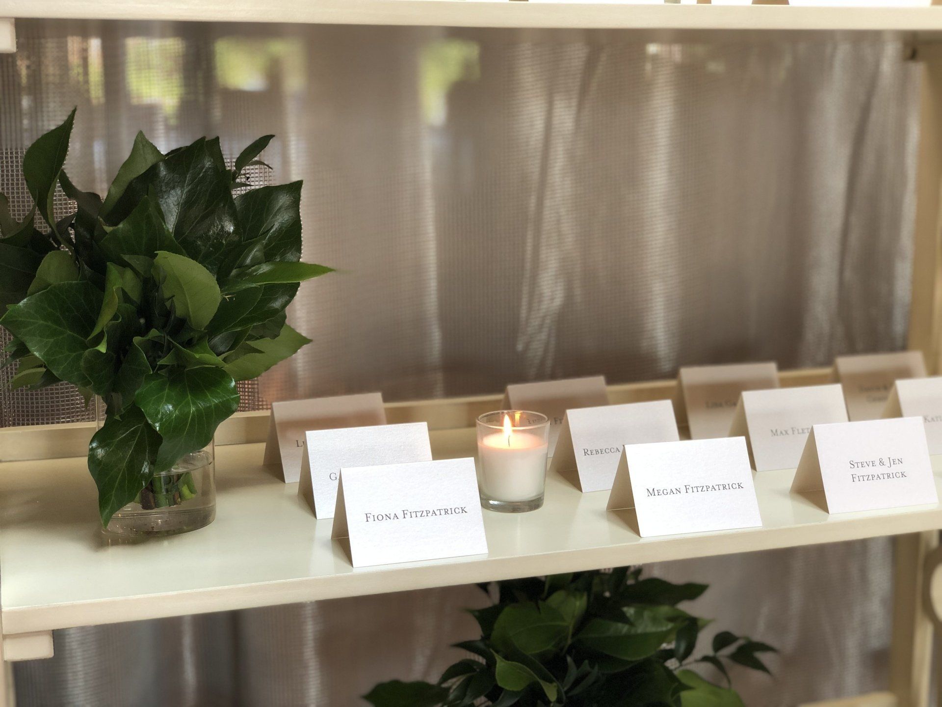 A shelf with a vase of flowers and a candle on it.