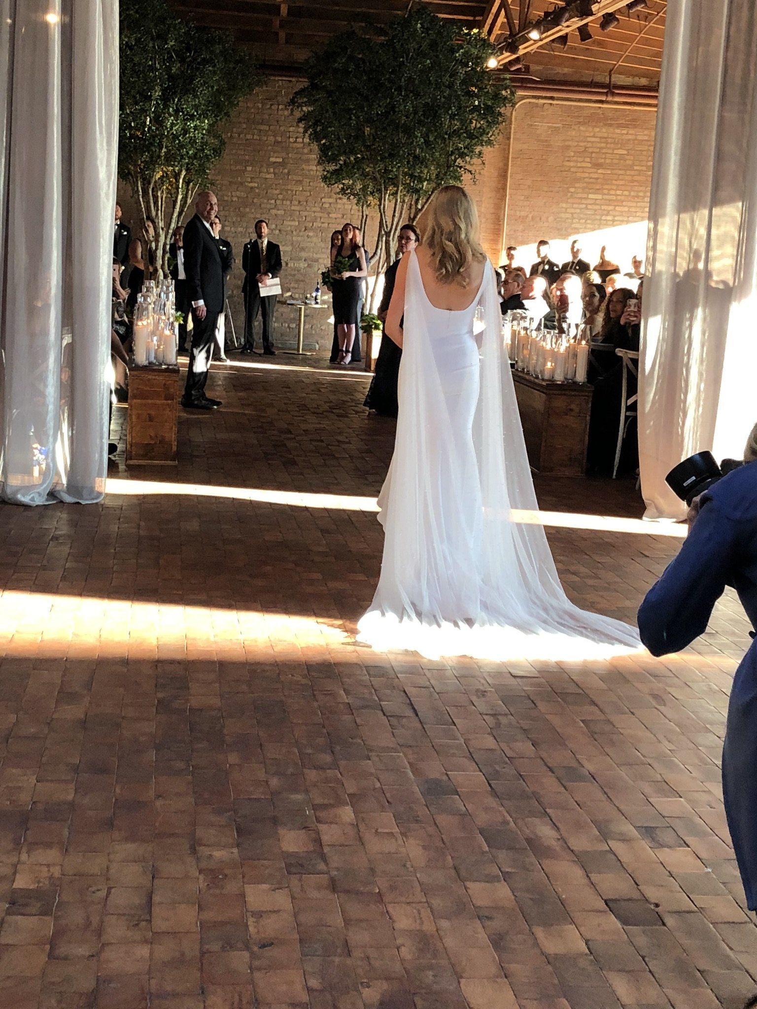 A woman is taking a picture of a bride in a wedding dress