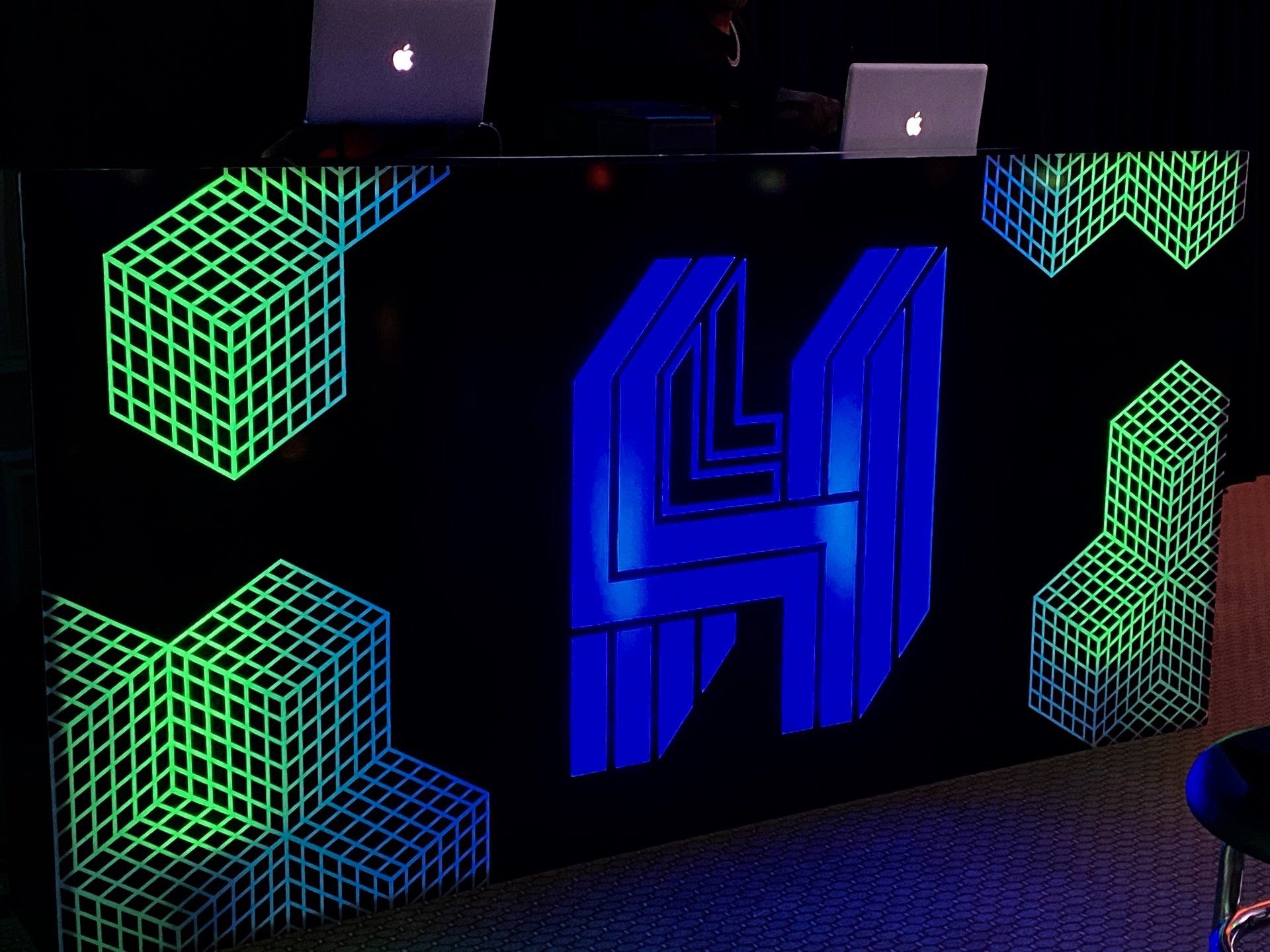 A dj booth with glow in the dark cubes and the letter h