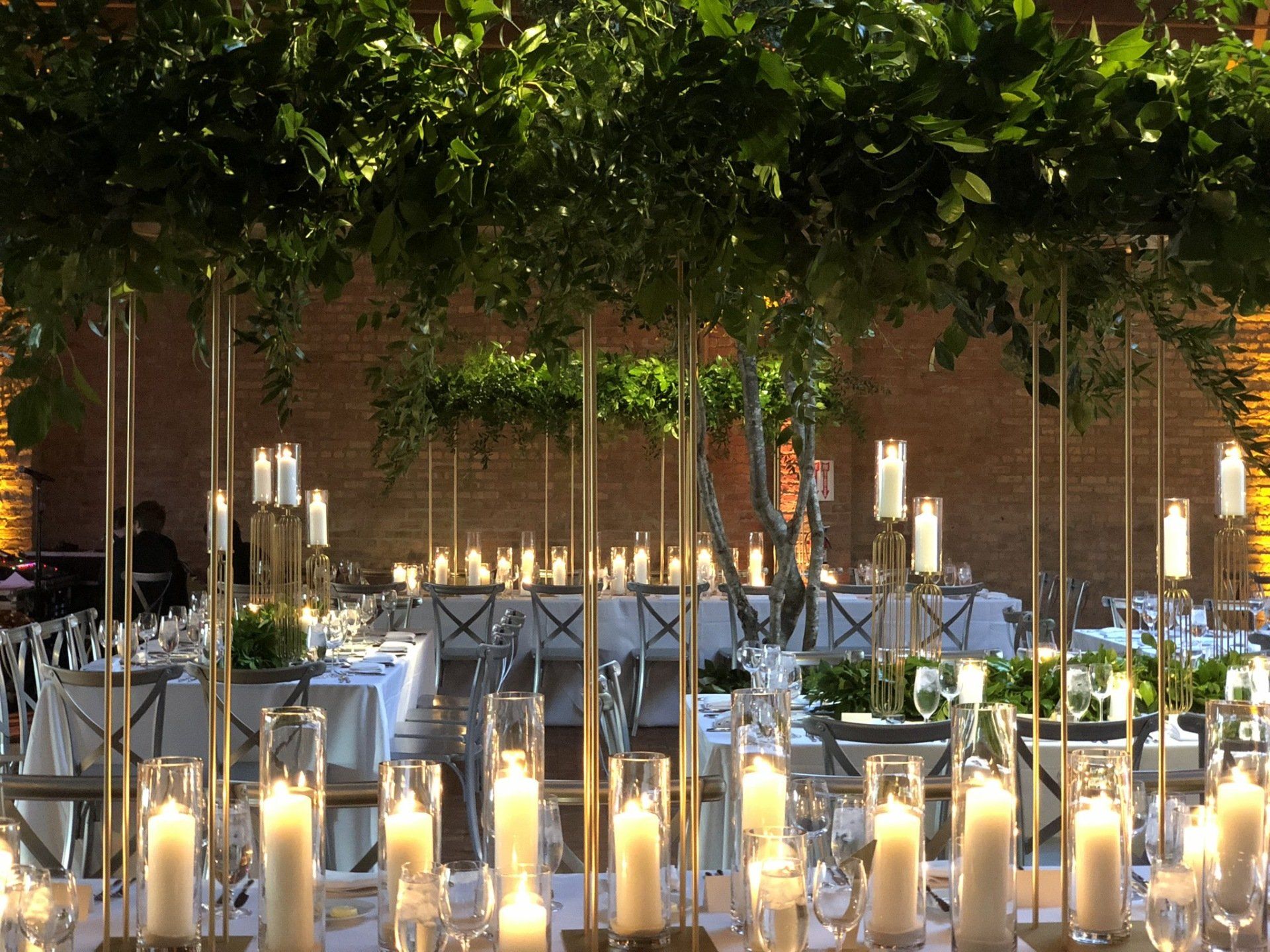 A long table with lots of candles and trees in the background.