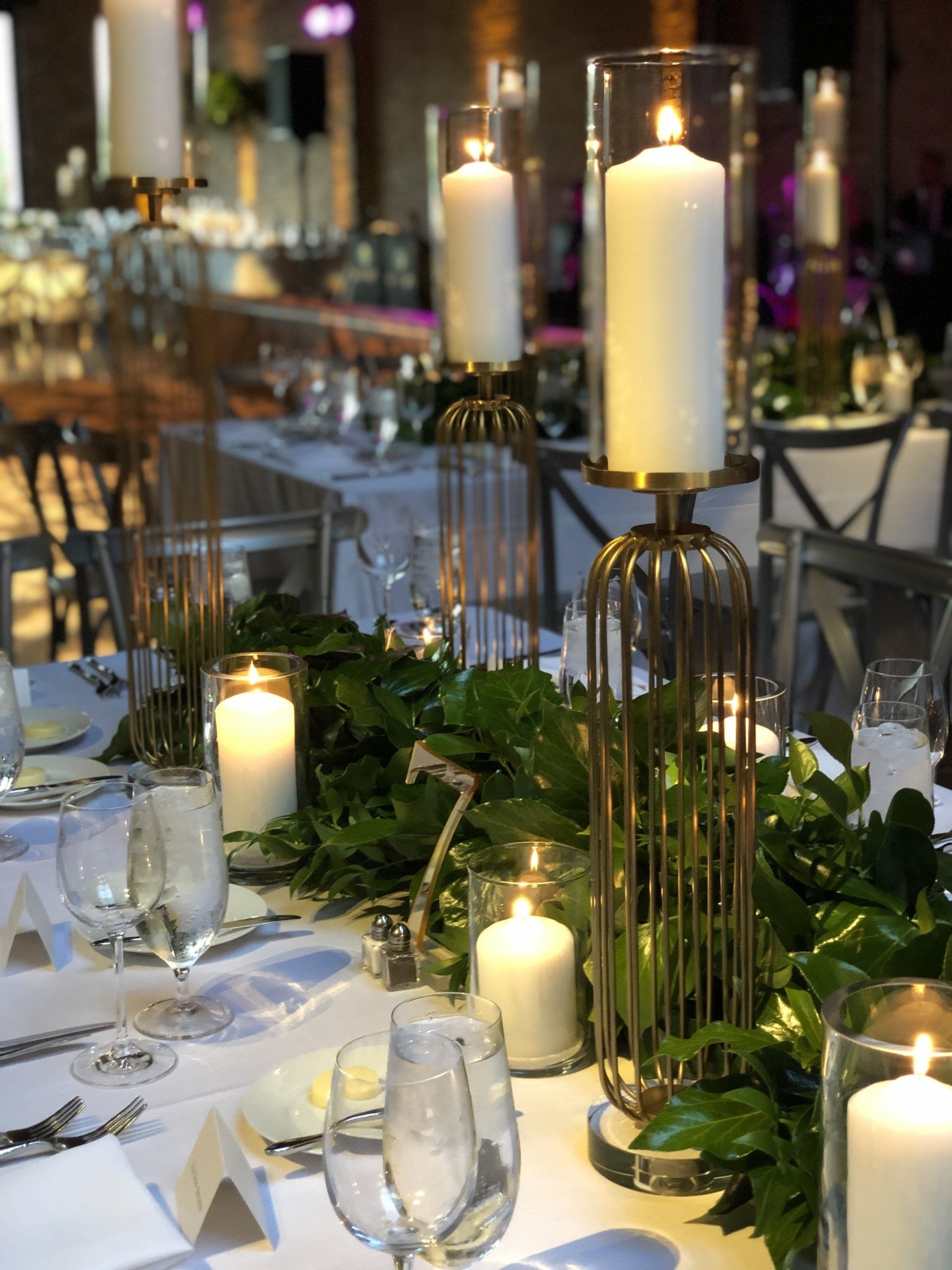 A table set for a wedding reception with candles and leaves on it.