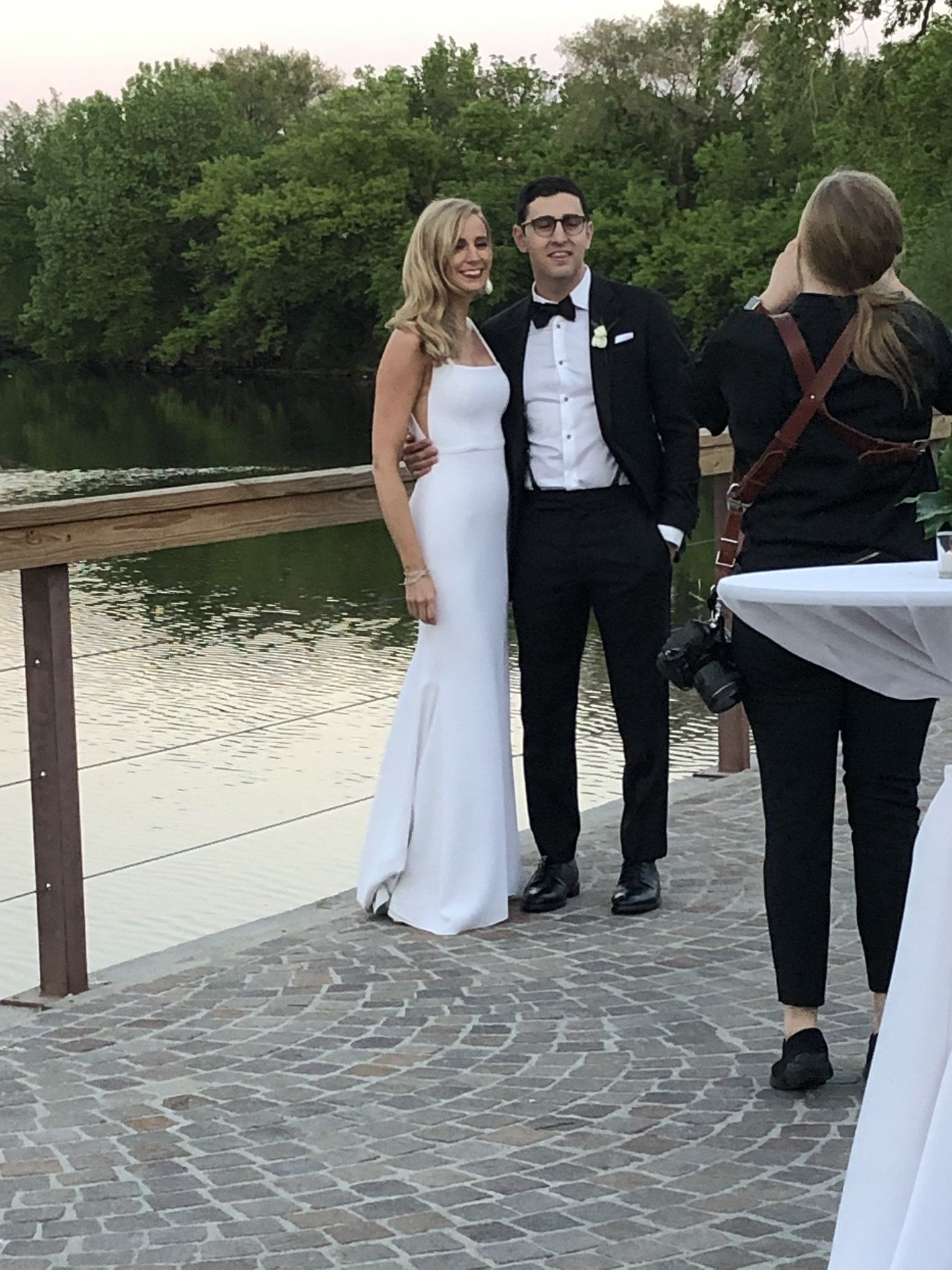 A bride and groom are posing for a picture in front of a lake.