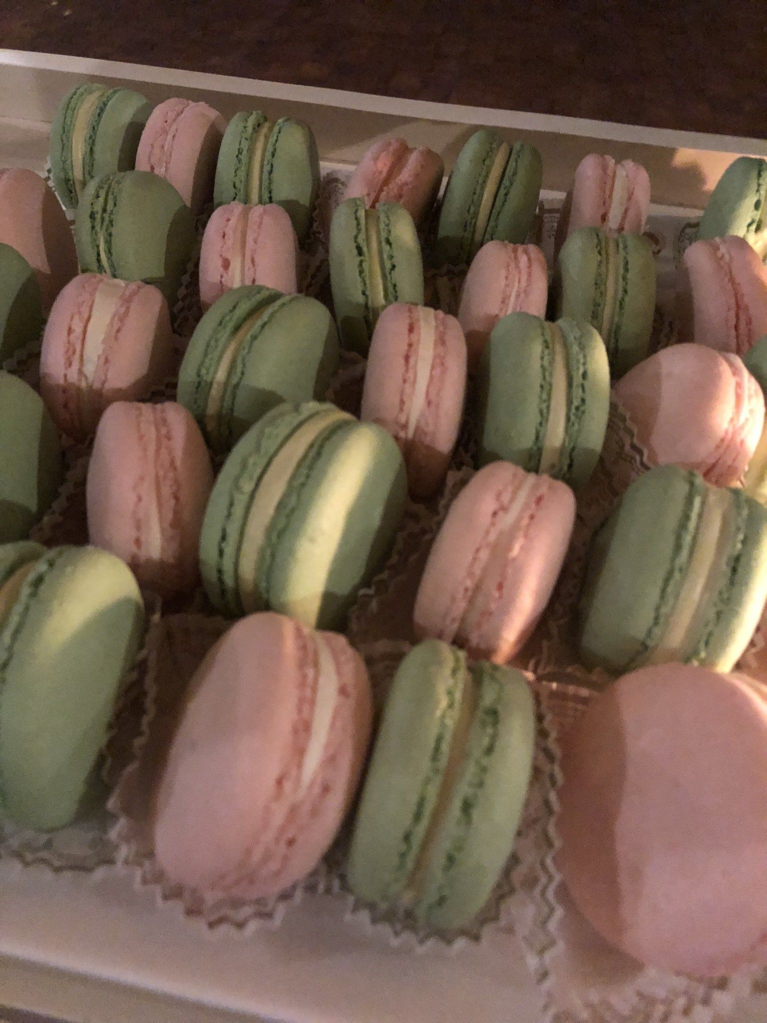 A tray of pink and green macarons on a table