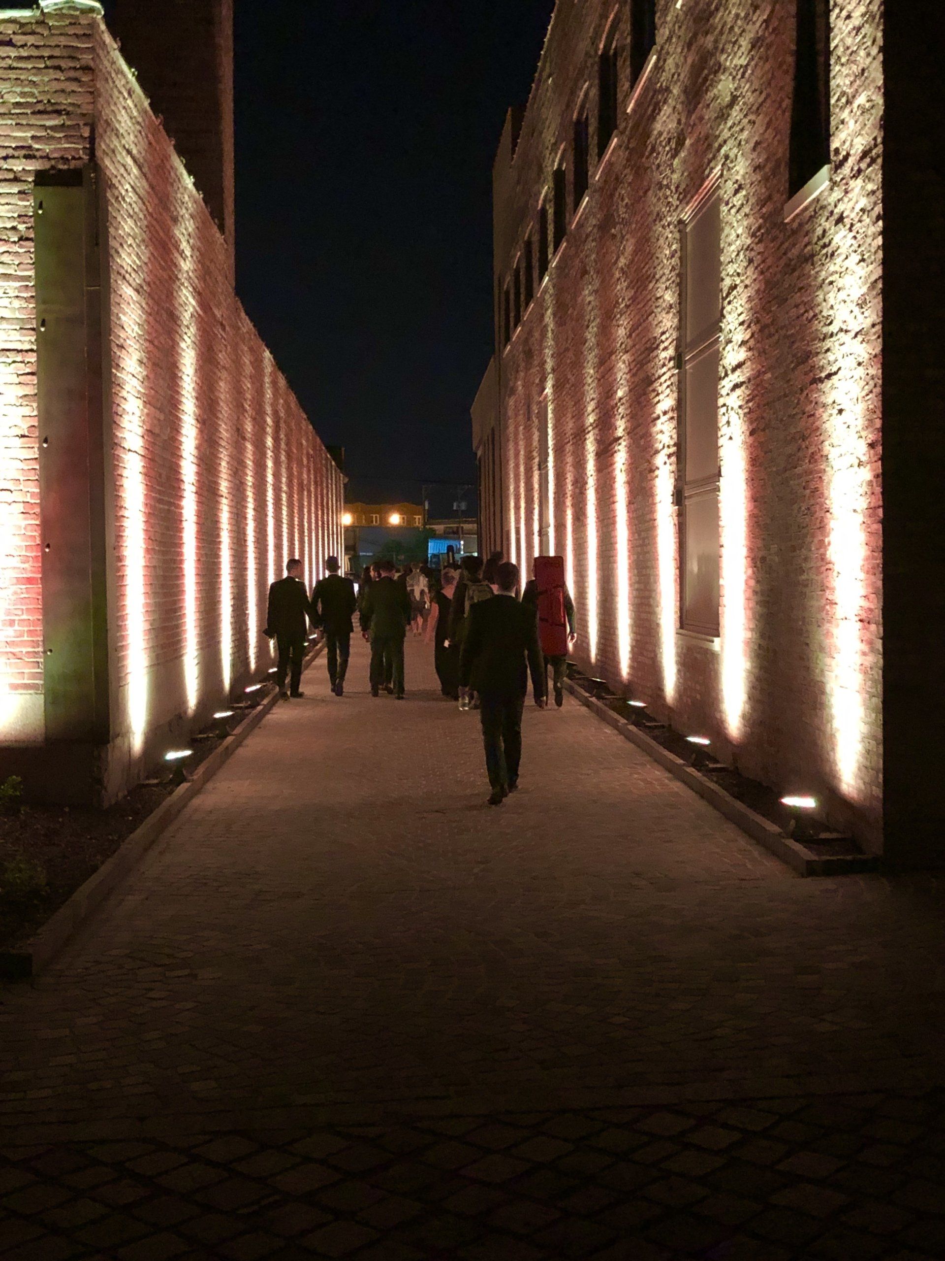 A group of people are walking down a hallway lit up at night