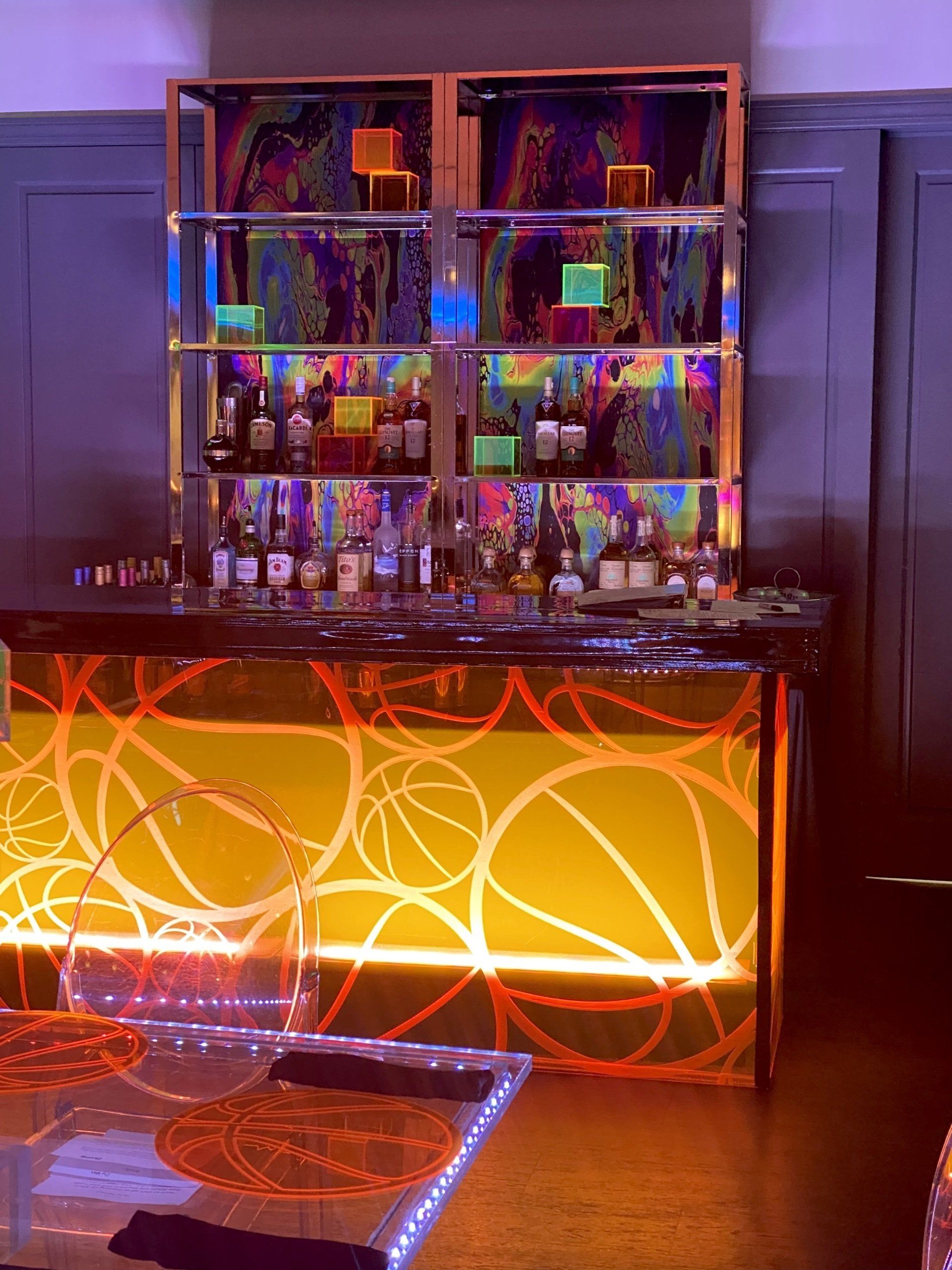 A bar with bottles on it and a table in front of it