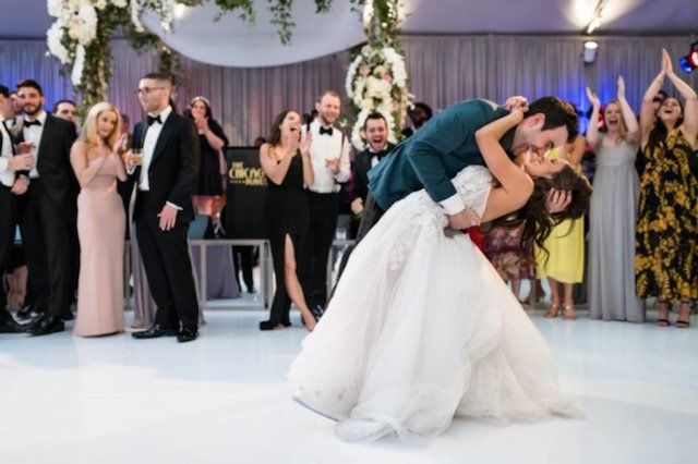 A bride and groom are kissing on the dance floor at their wedding reception.