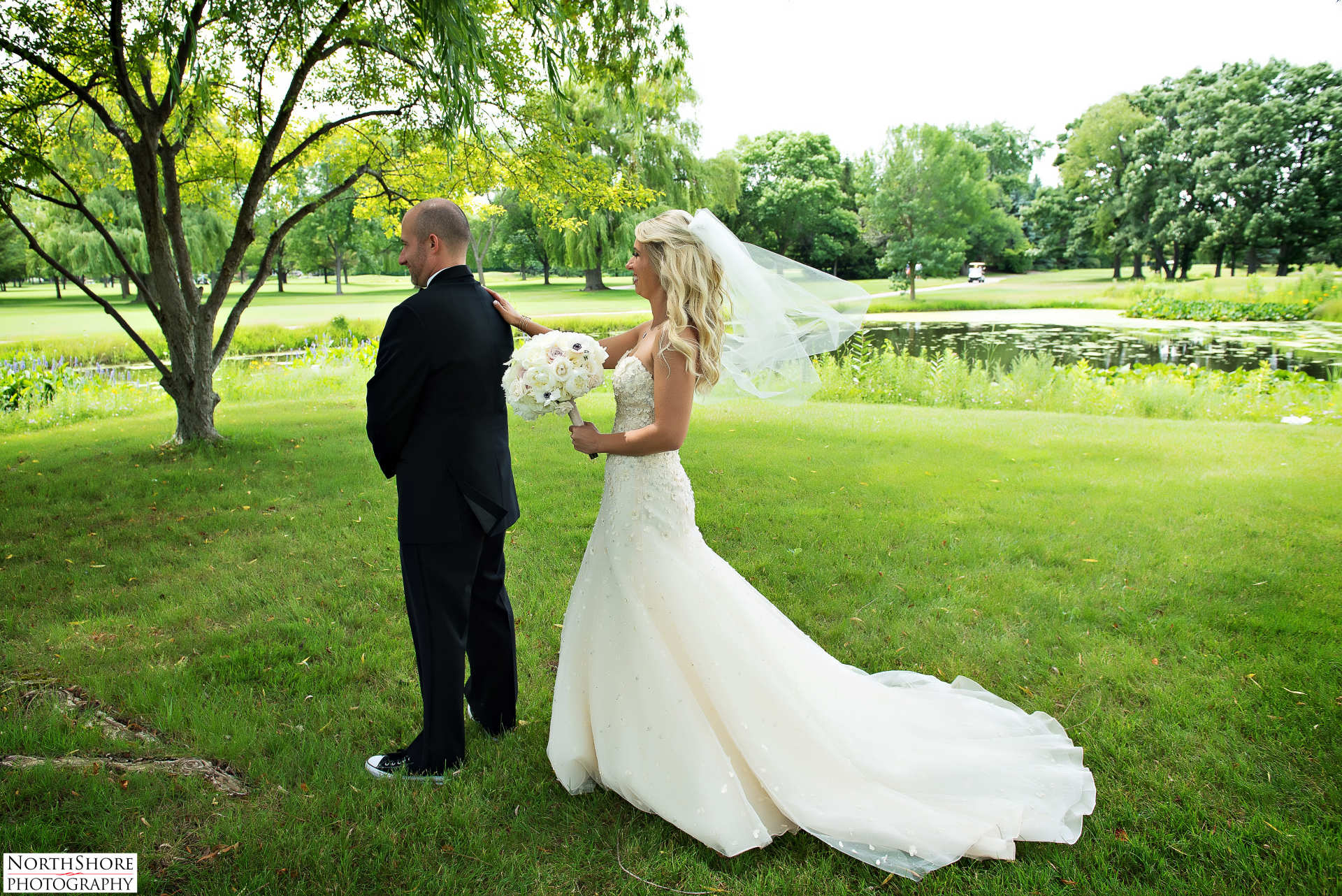 A bride and groom are standing in a grassy field