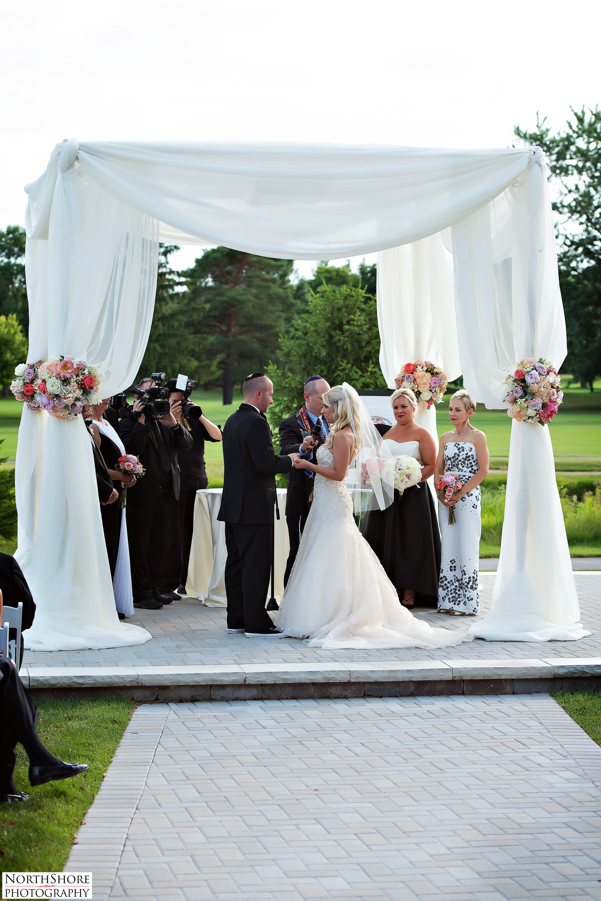 A bride and groom are getting married under a white canopy.