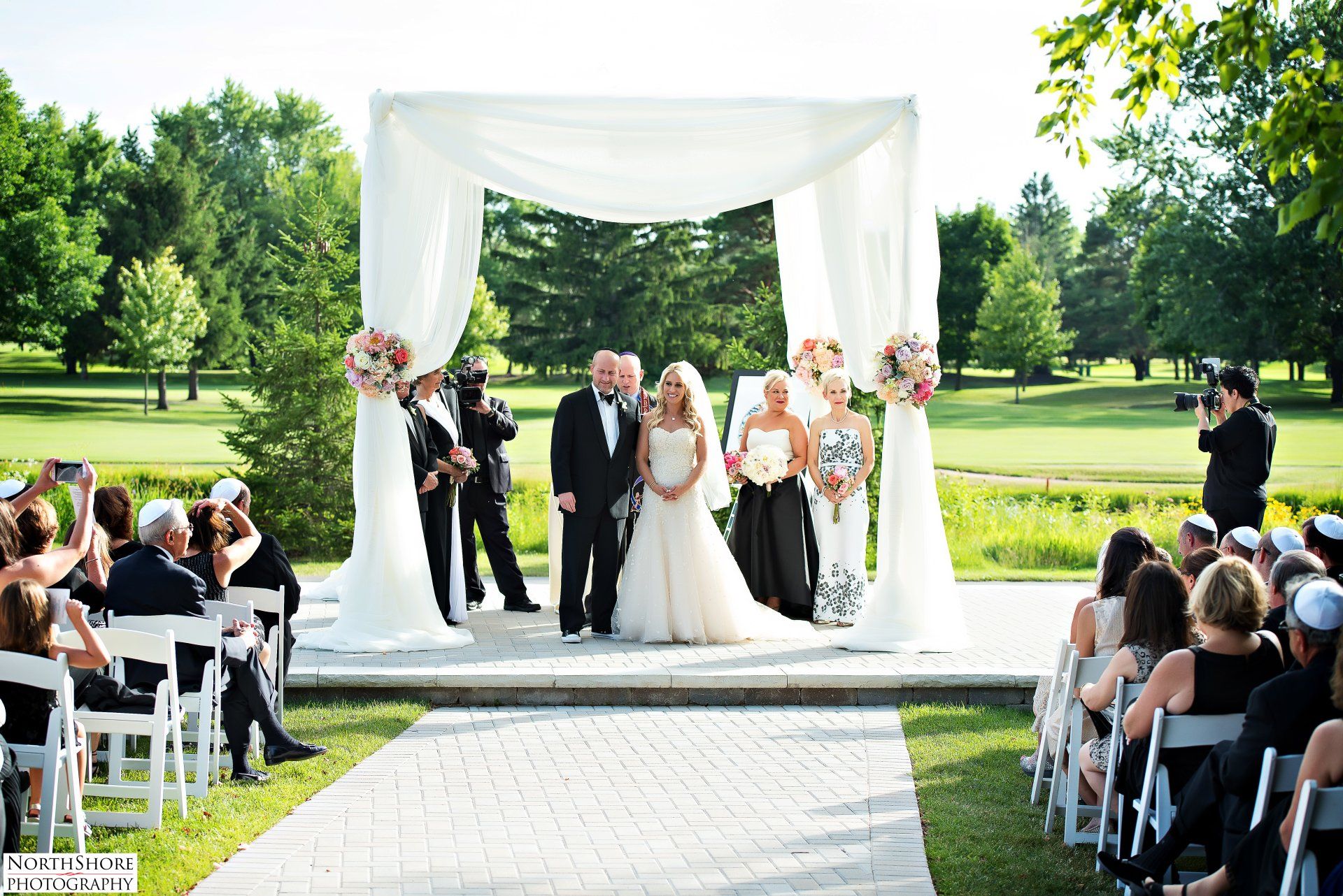 A bride and groom are getting married under a white canopy