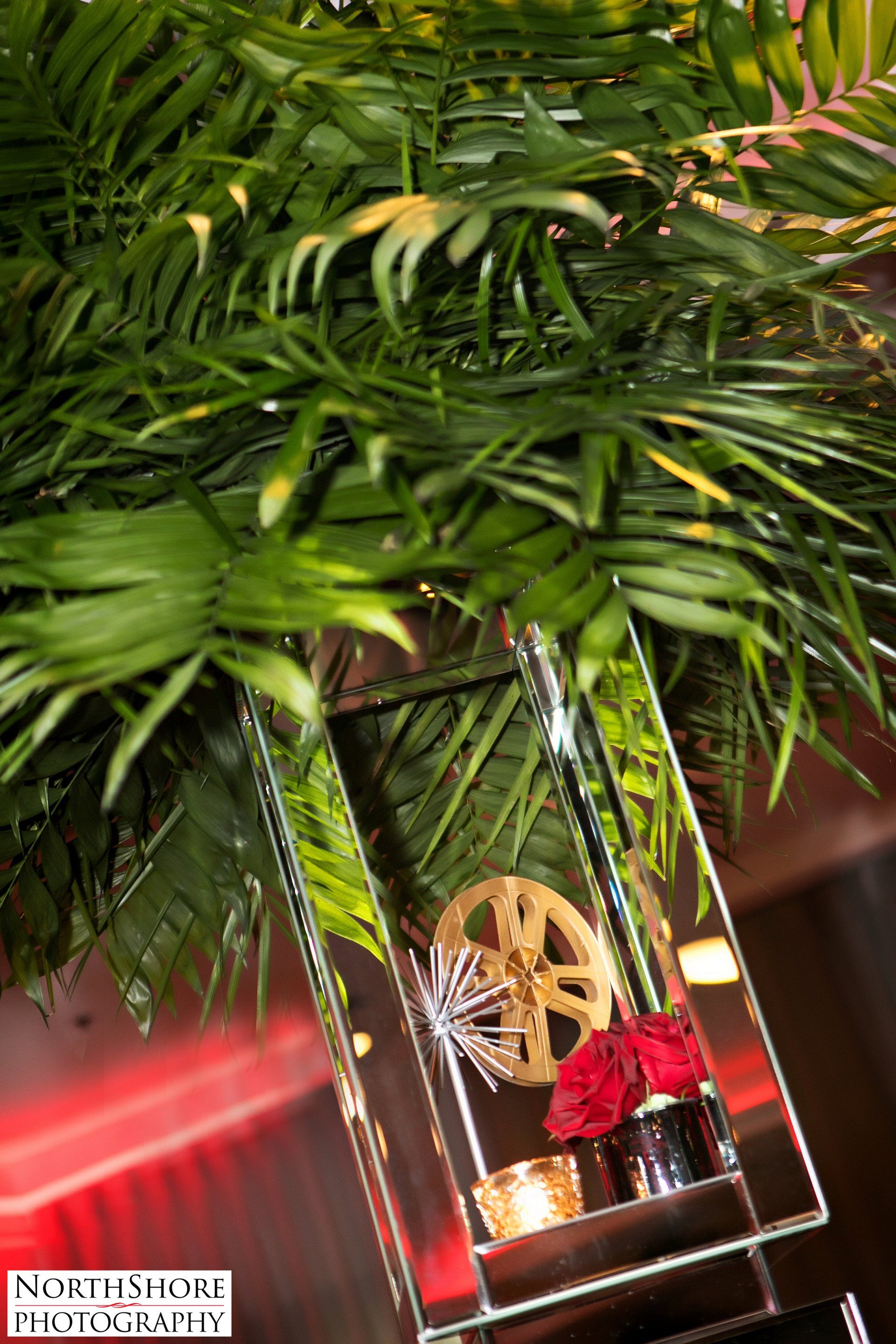 A glass vase filled with flowers and a movie wheel.