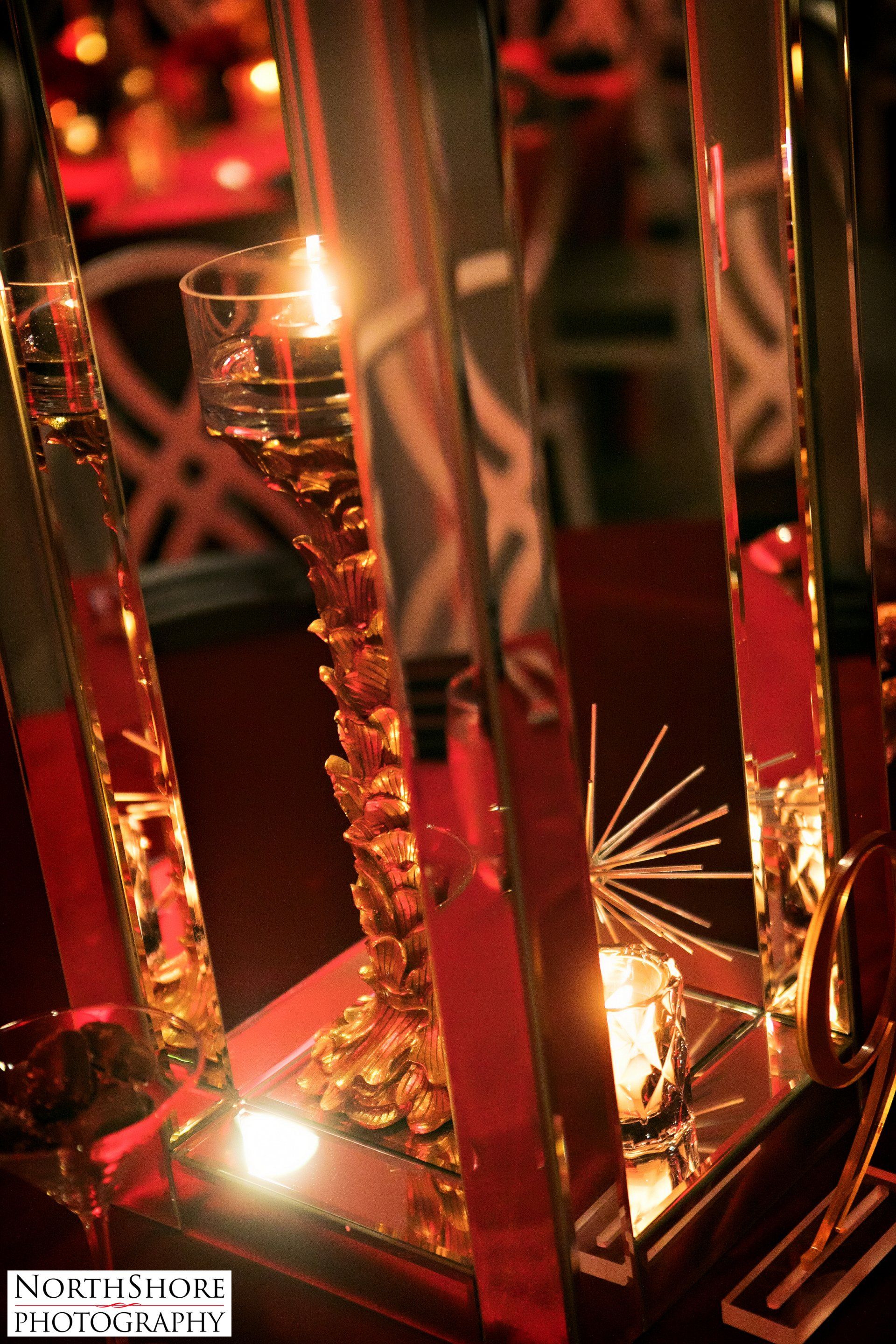 A candle is lit in a glass vase on a table.
