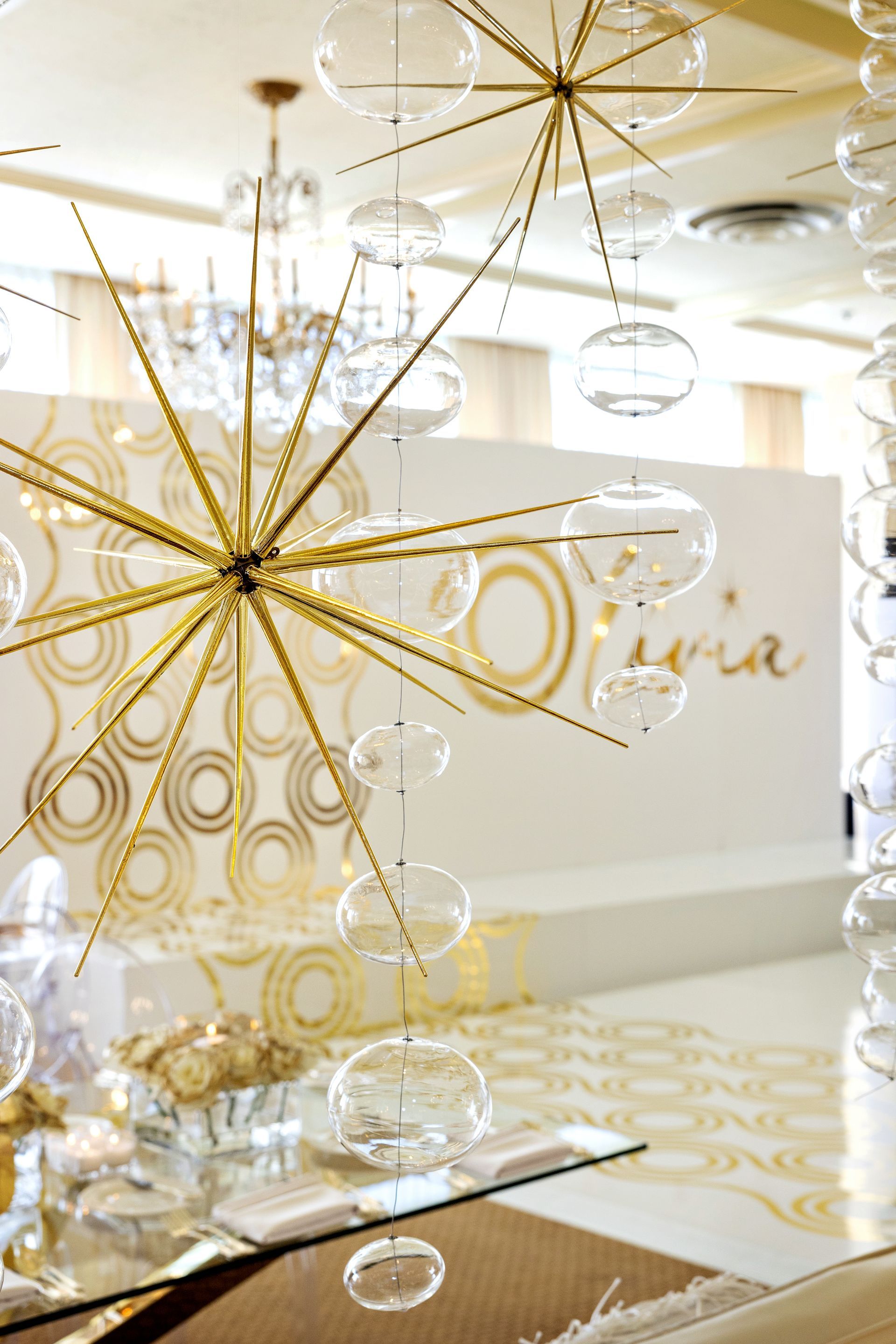 A room with a glass table and a chandelier hanging from the ceiling.