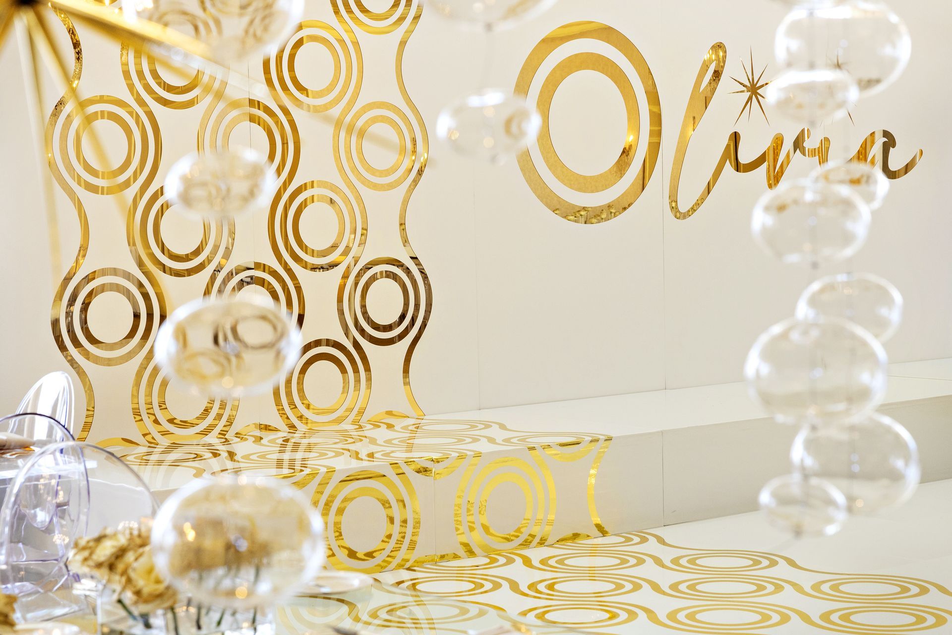 A white wall with gold circles and bubbles hanging from it.