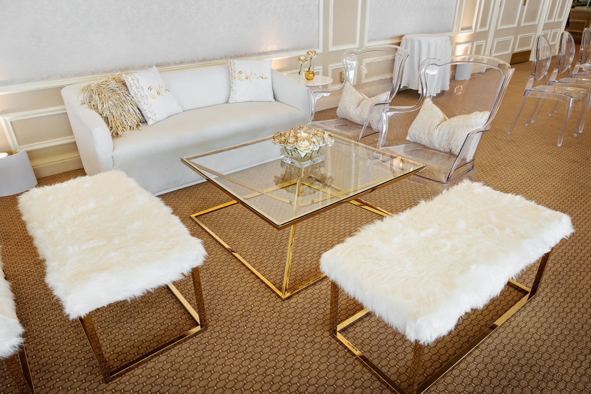 A living room with white furniture and a glass coffee table.