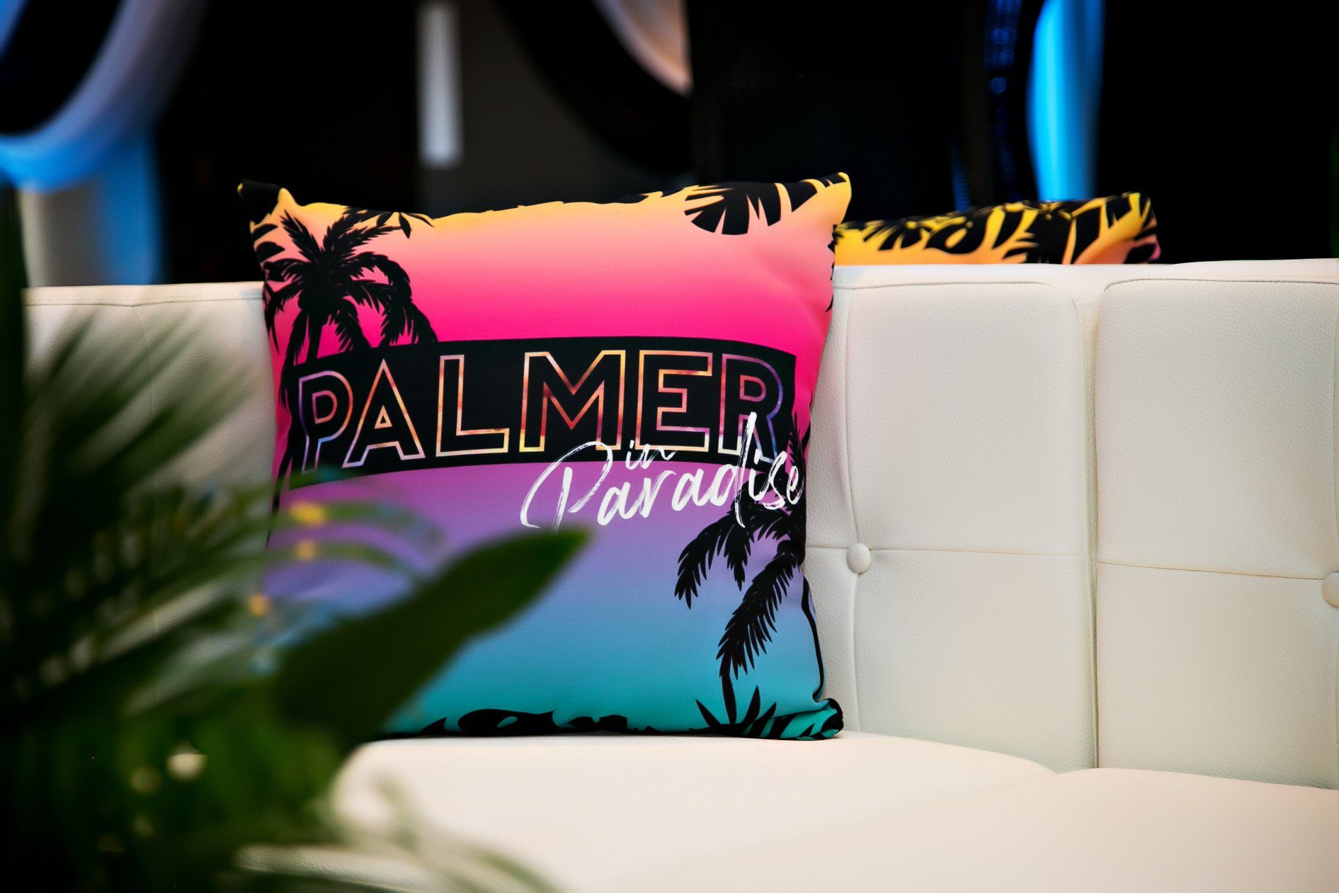 A palmer paradise pillow is sitting on a white couch.
