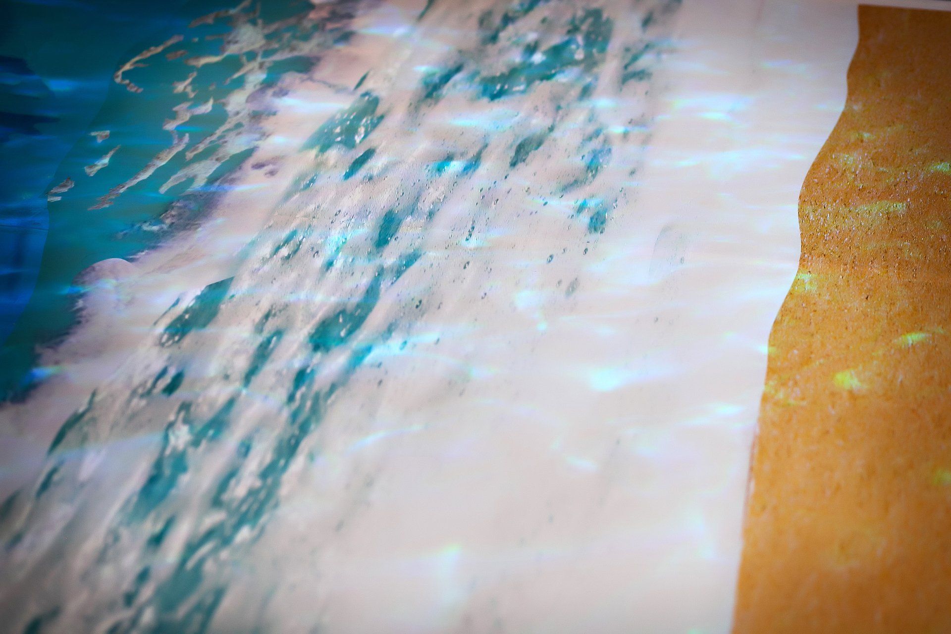 A close up of a painting of waves crashing on a beach.