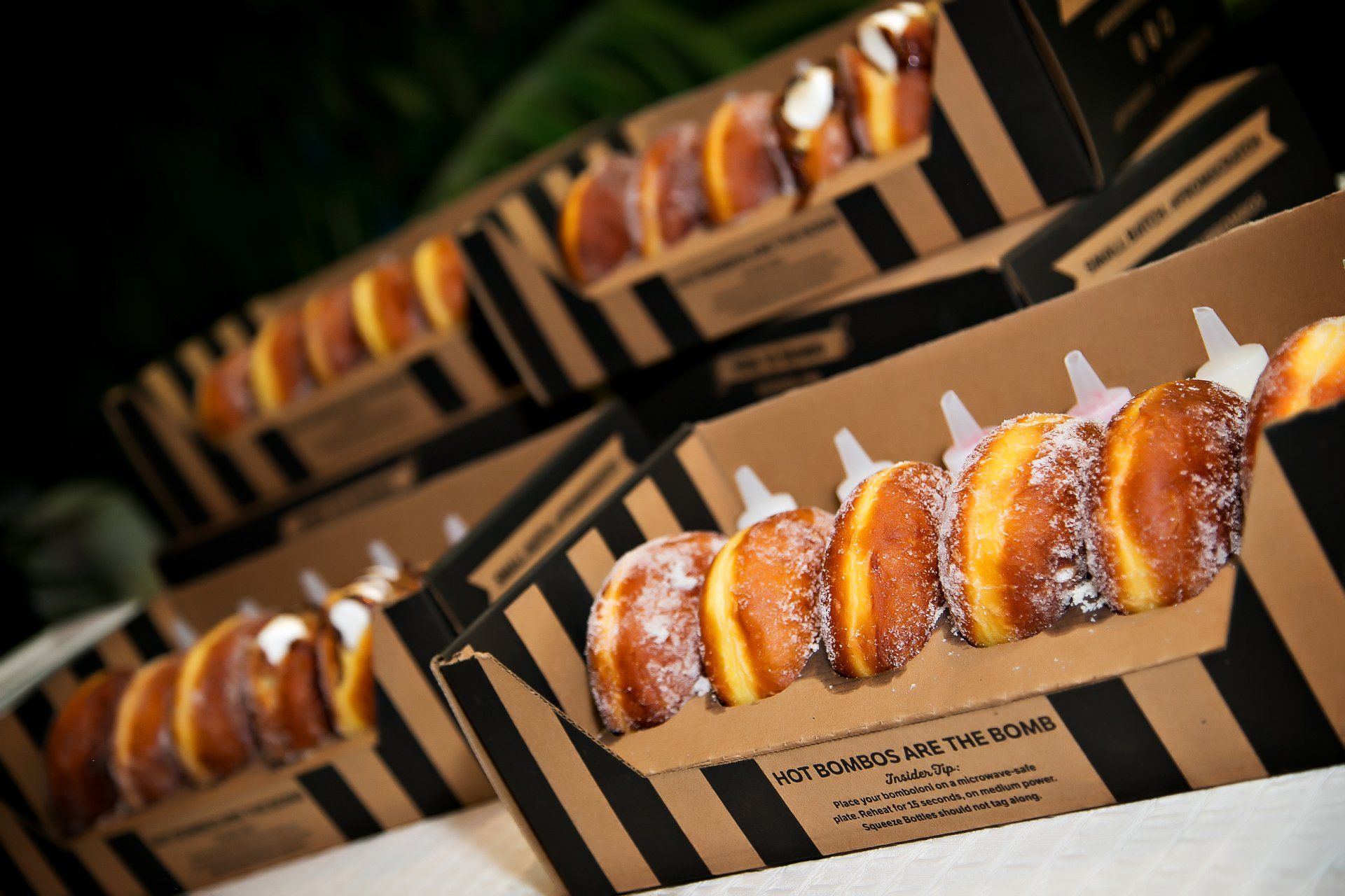 A row of donuts in cardboard boxes on a table
