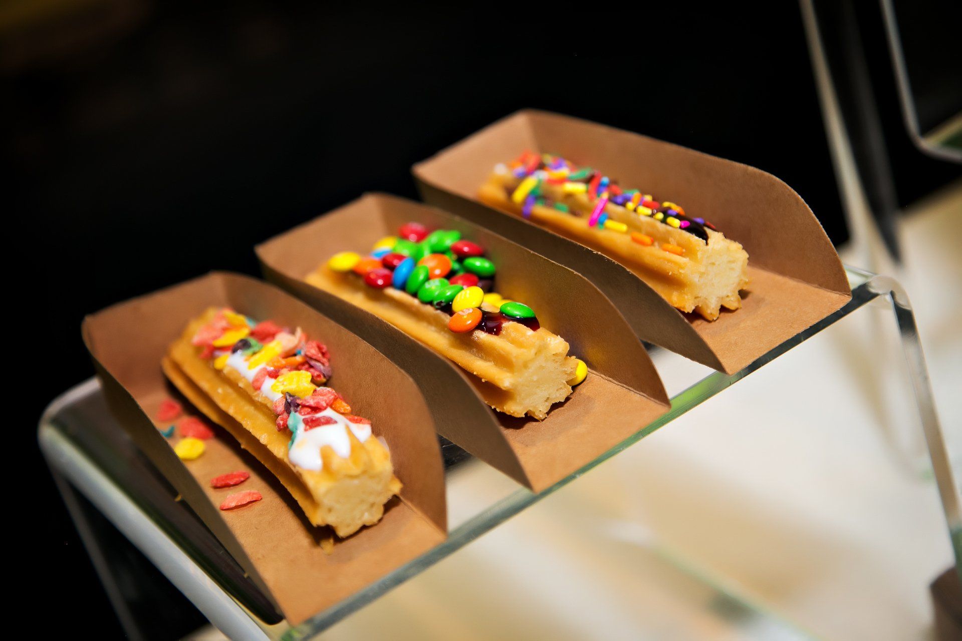 Three churros with sprinkles on them are on a tray.