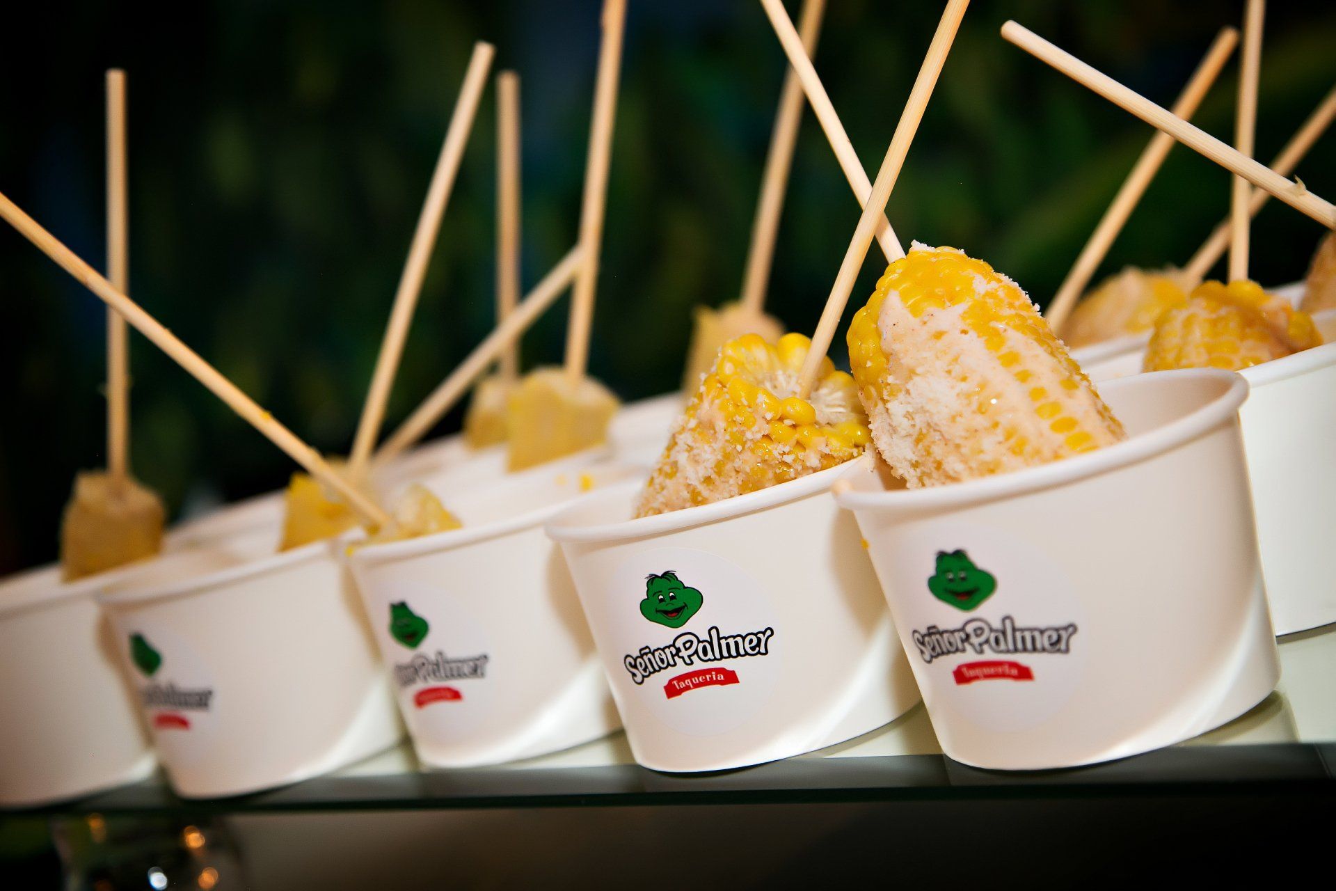 A row of cups filled with corn on the cob