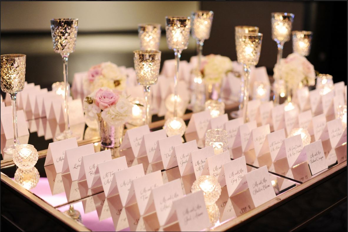 A table with place cards and candles on it