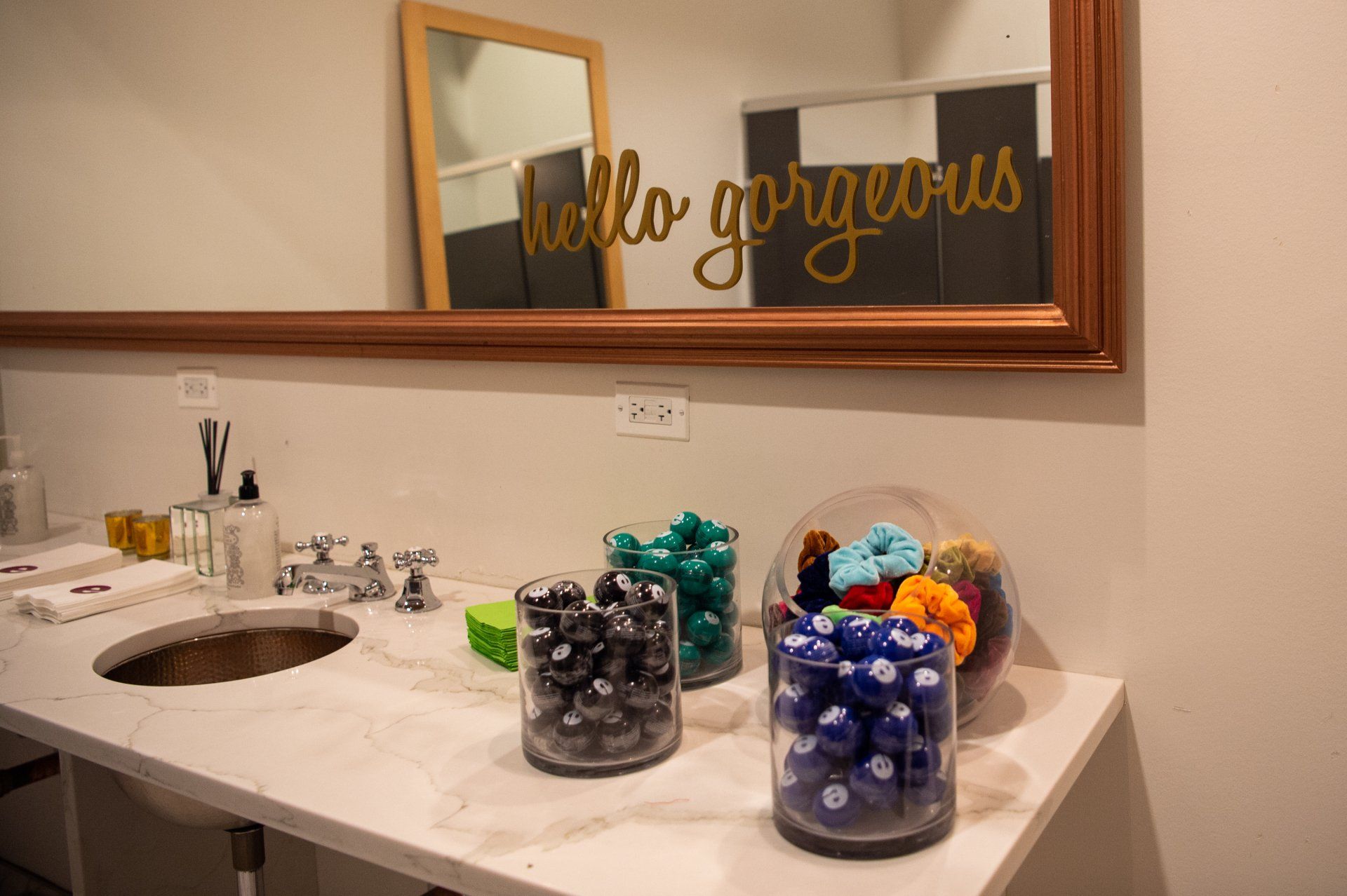 A bathroom with a sink , mirror and a sign that says `` hello gorgeous ''.