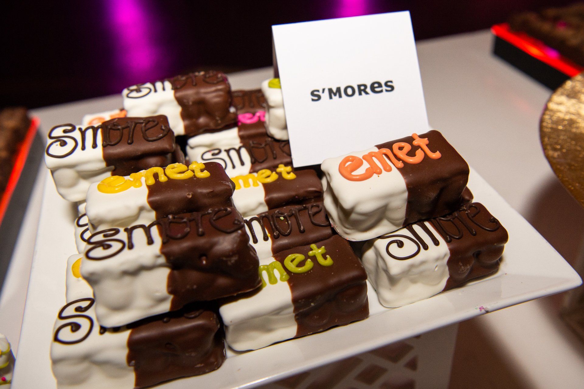 A white plate topped with chocolate covered s'mores on a table.