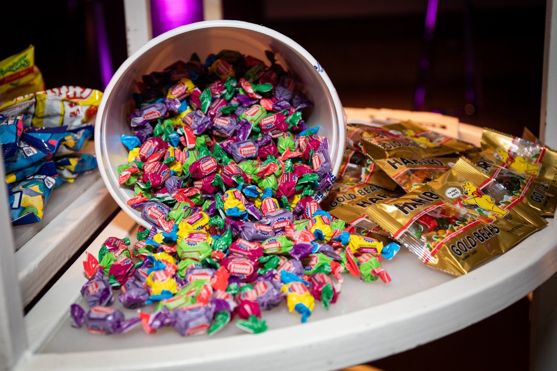 A bucket of candy is spilling out onto a table.