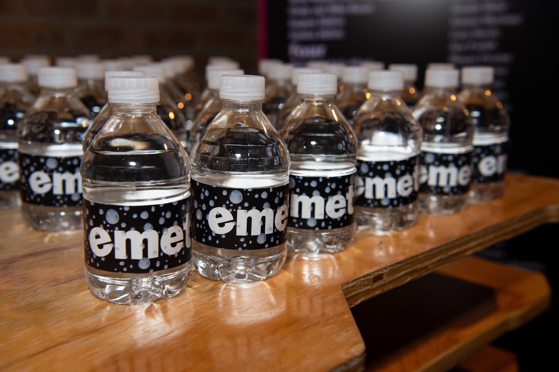 A row of water bottles with labels that say eme on them