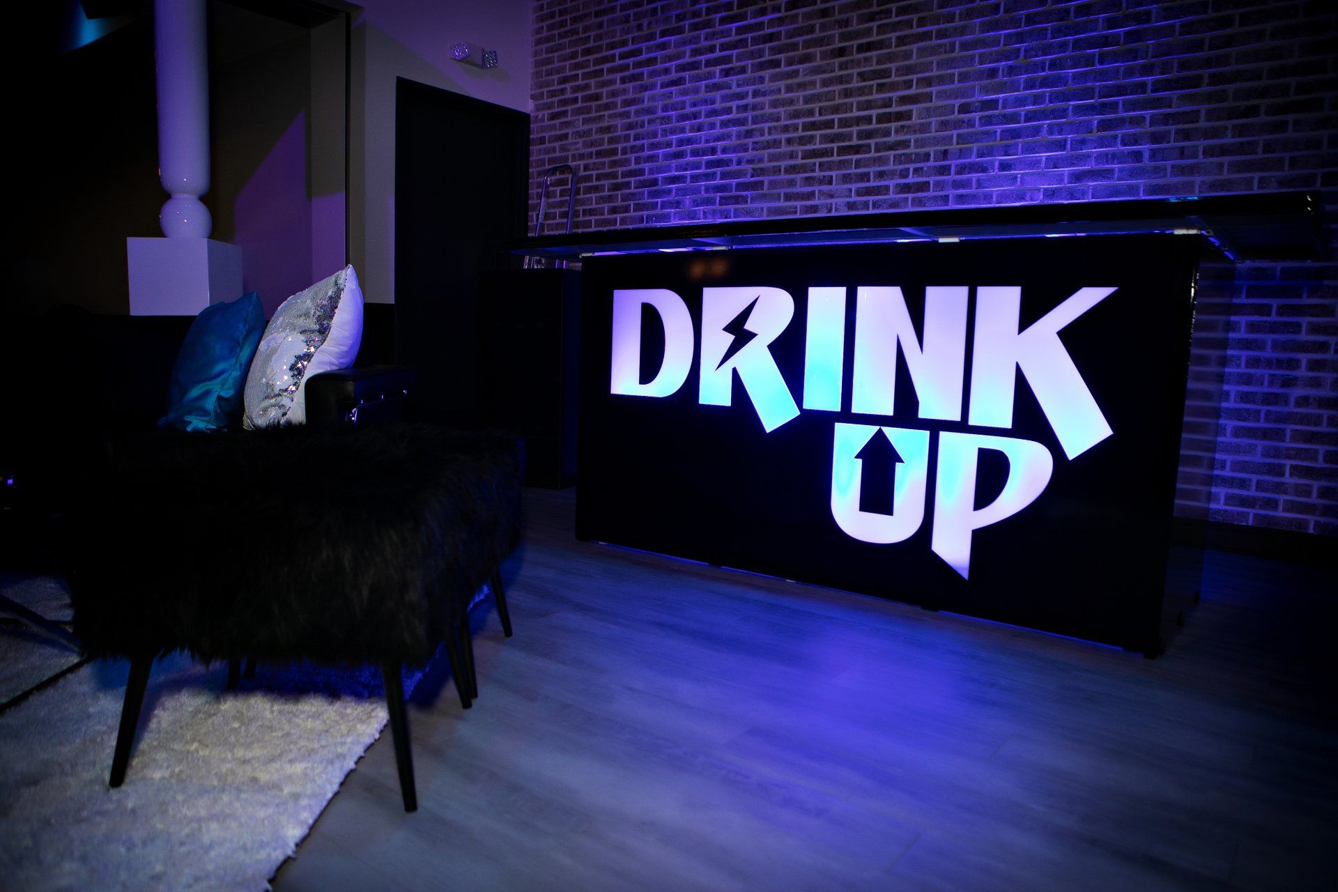 A drink up sign is lit up in a living room.