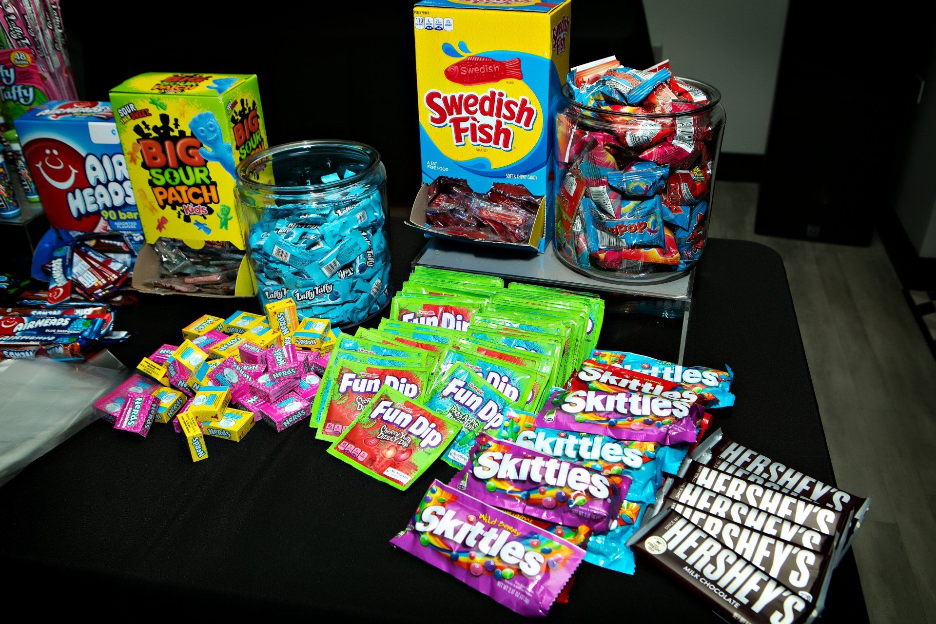 A table topped with a variety of candy including skittles and hershey 's.