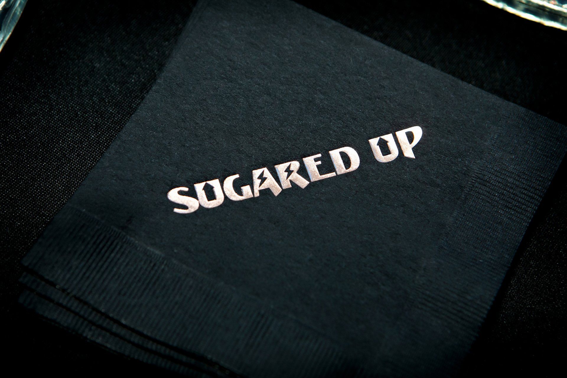 A black napkin that says sugared up on it