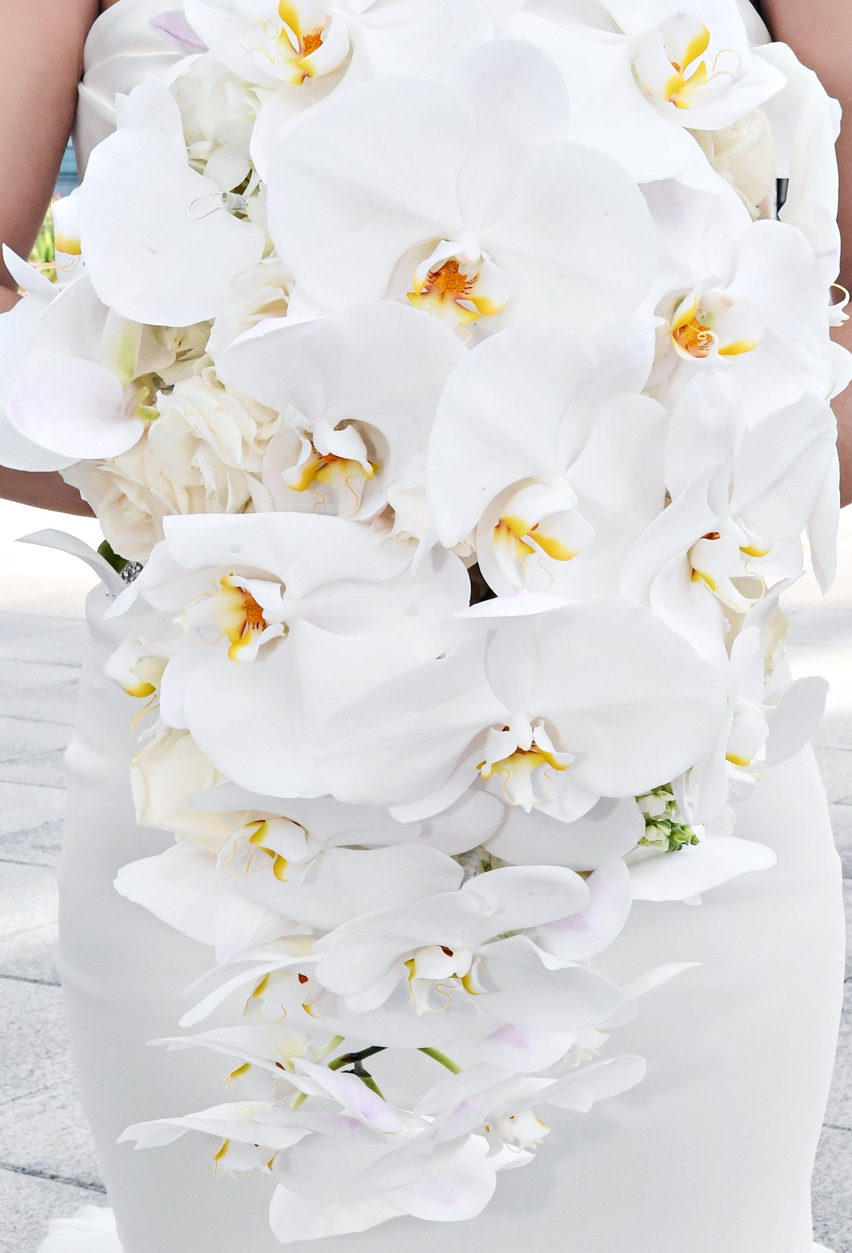 A bride in a white dress is holding a bouquet of white flowers.