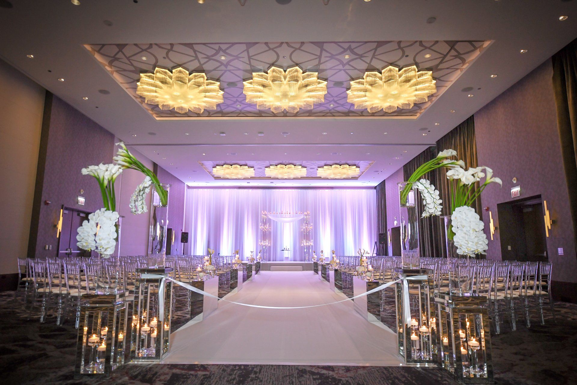 A large room decorated for a wedding ceremony with candles and flowers.