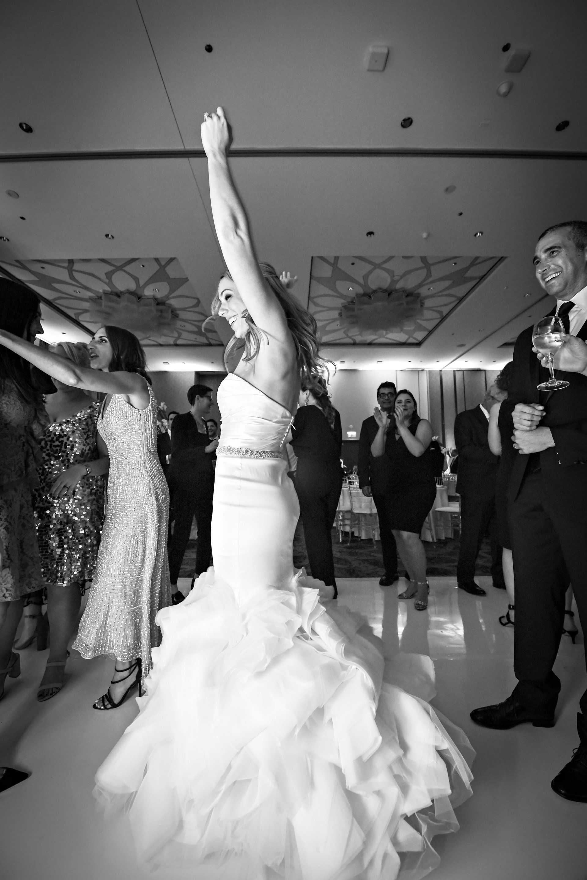 A black and white photo of a bride dancing at a wedding reception.